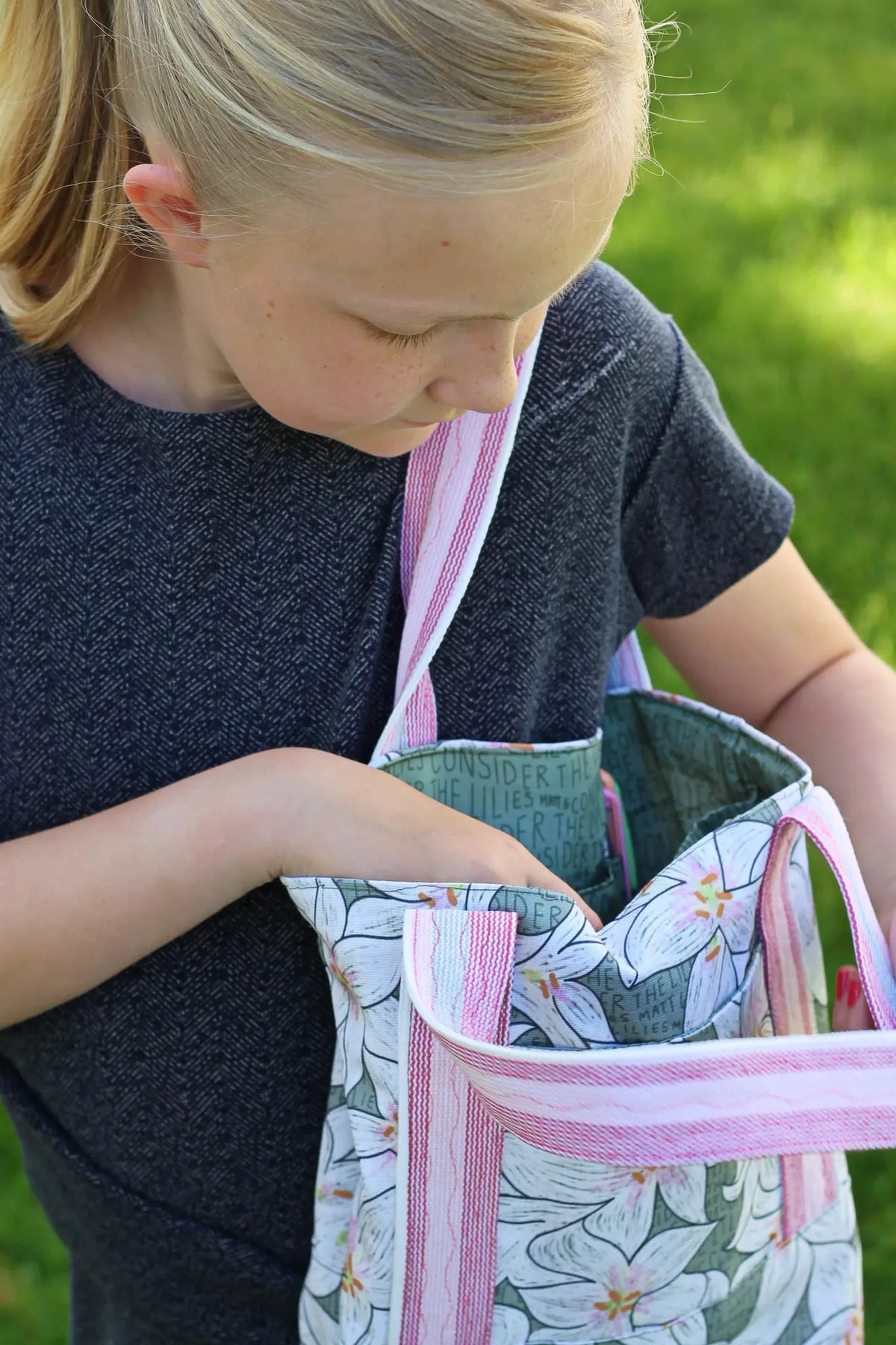A young girl holds a bag made from Lilies in Green fabric.