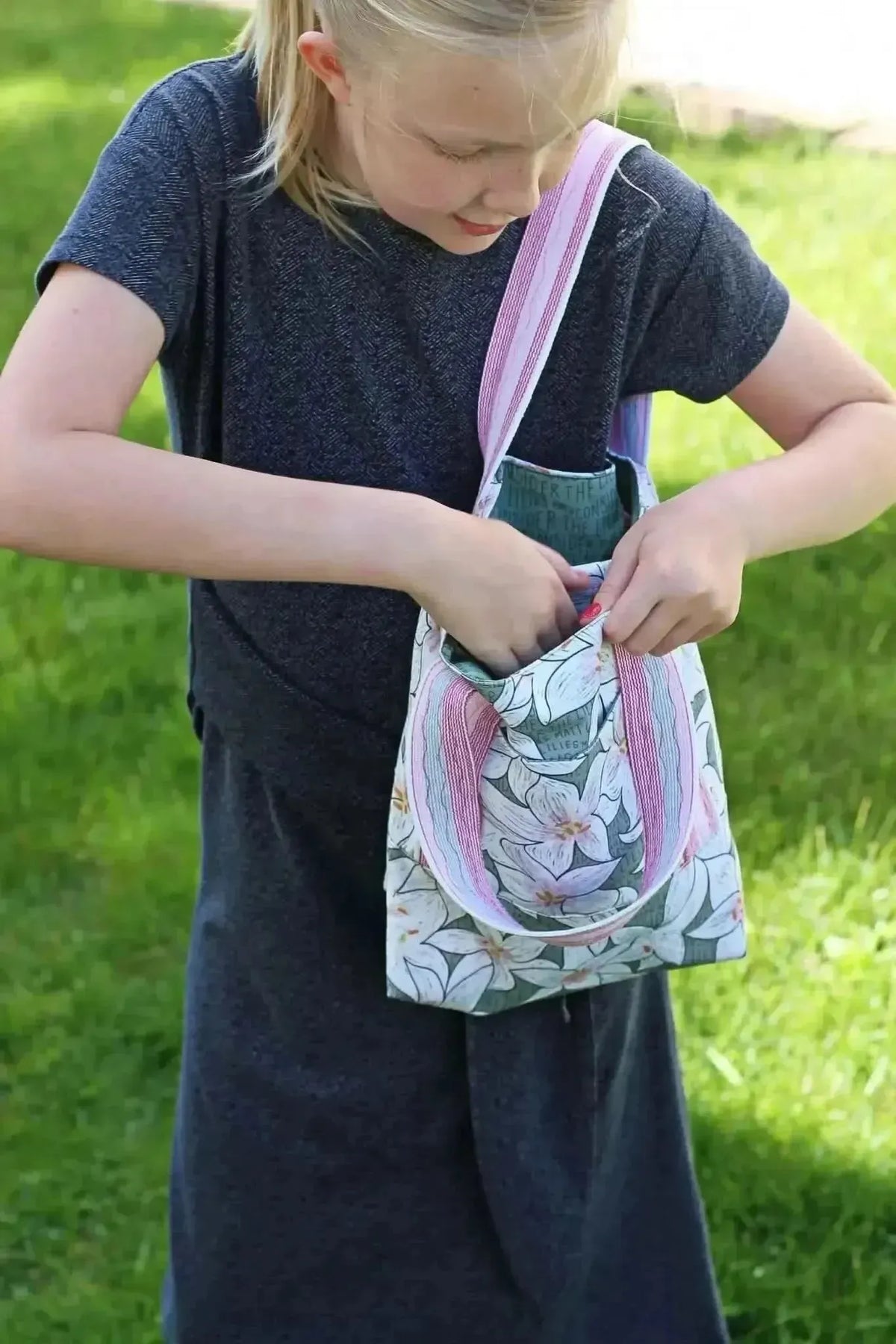 A child holds a tote bag made from botanical print fabric with lilies in green.