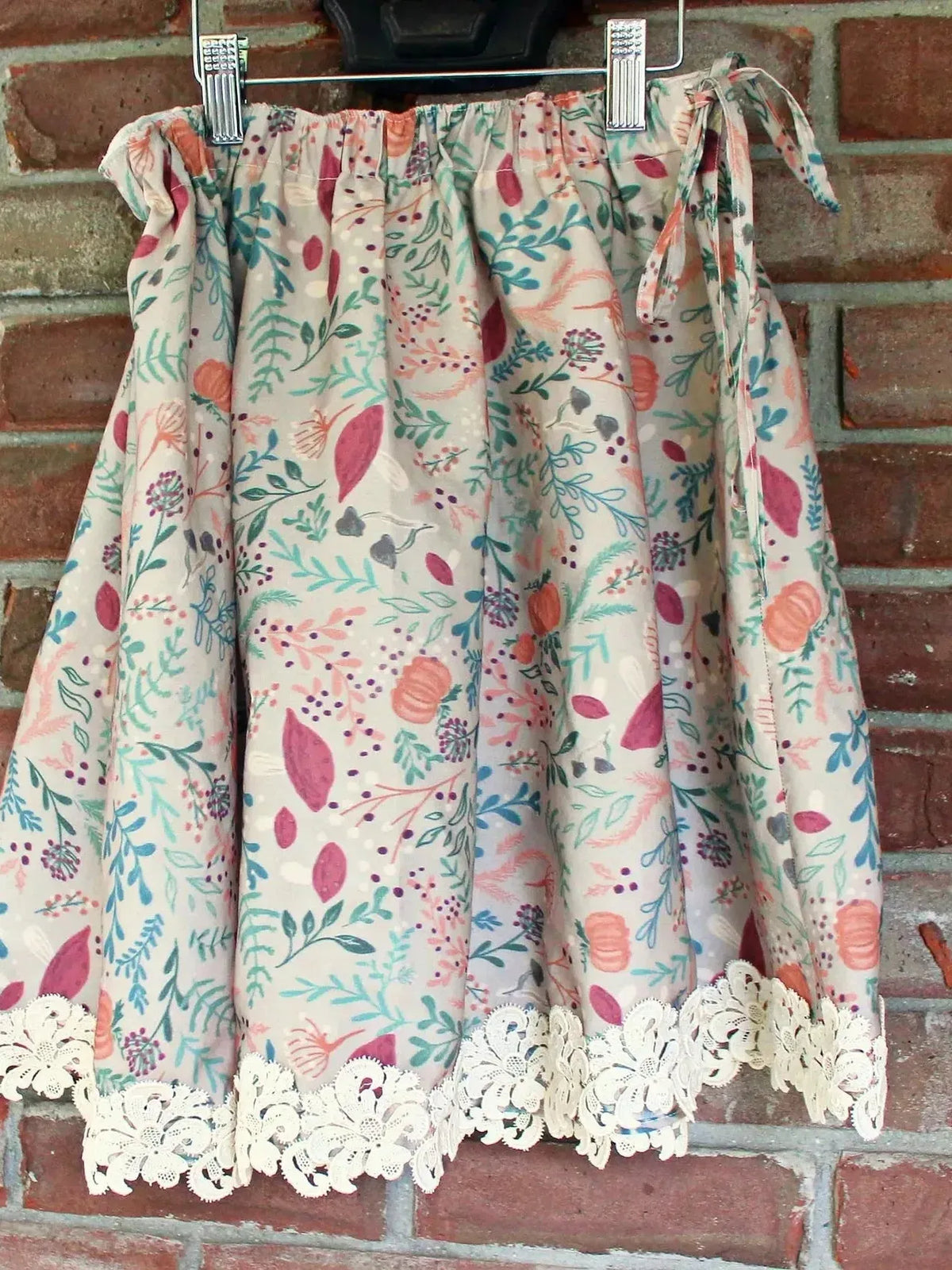 Tan botanical fabric with forest foliage print in pink and green tones.