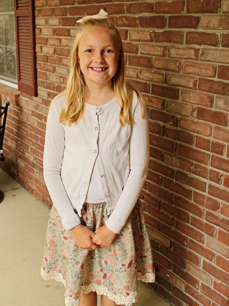 Tan botanical fabric with forest foliage print on a white cardigan and skirt.