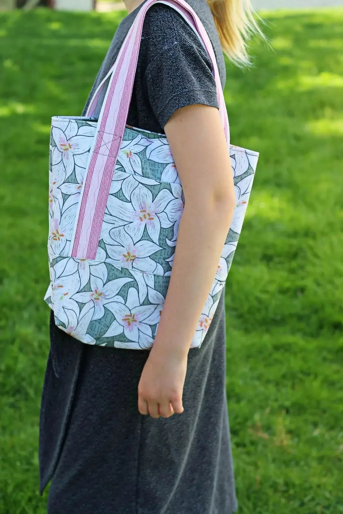 Lilies in green botanical print fabric with white and pink flowers on a tote bag.