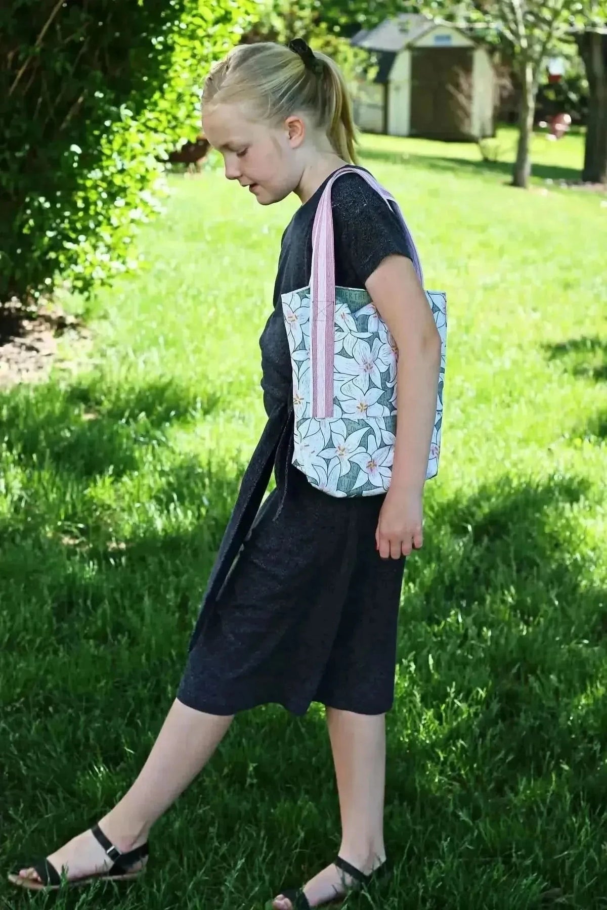 A young girl carries a tote bag made from Lilies in Green botanical print fabric.