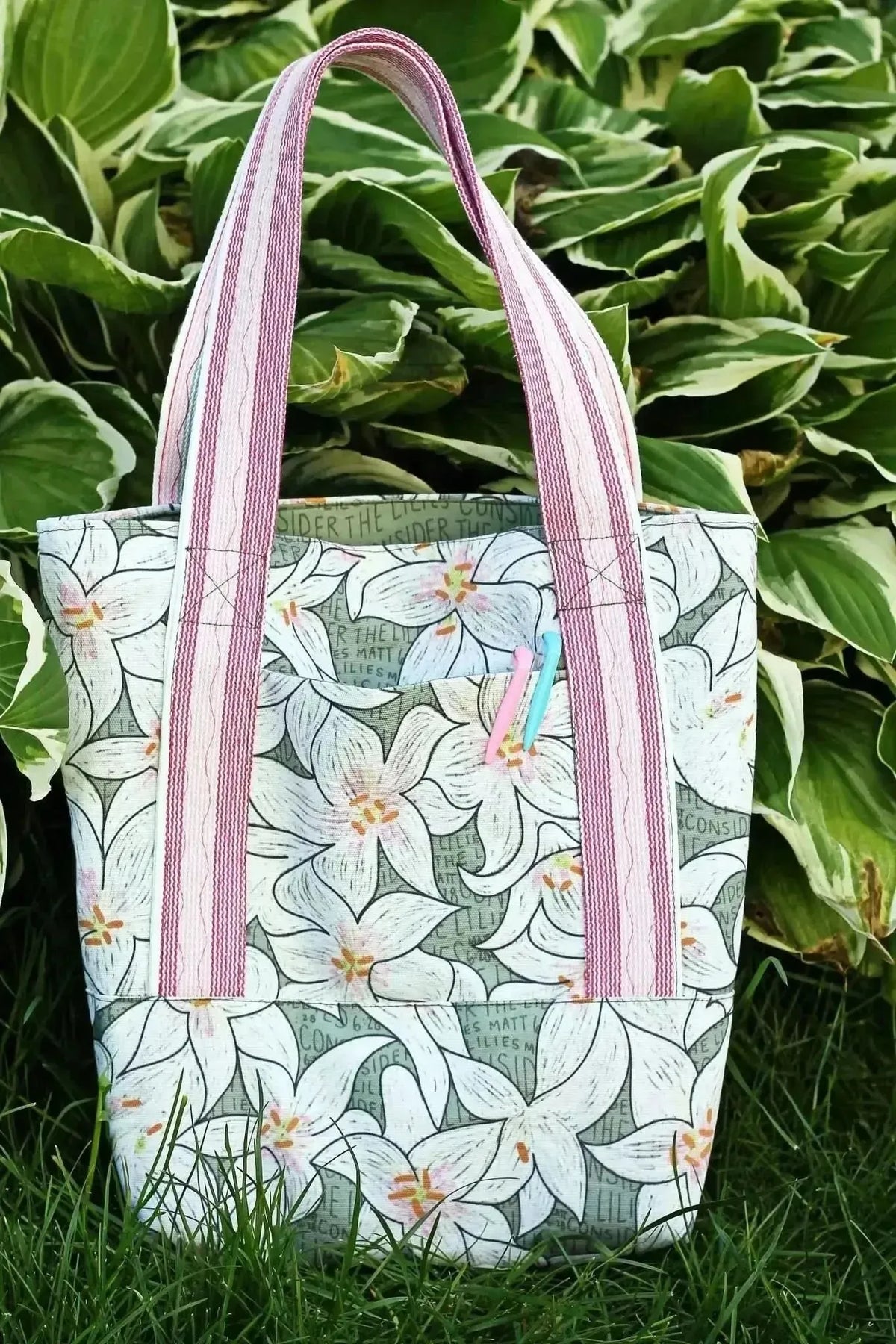 Lilies in green botanical print fabric with pink accents on a tote bag.