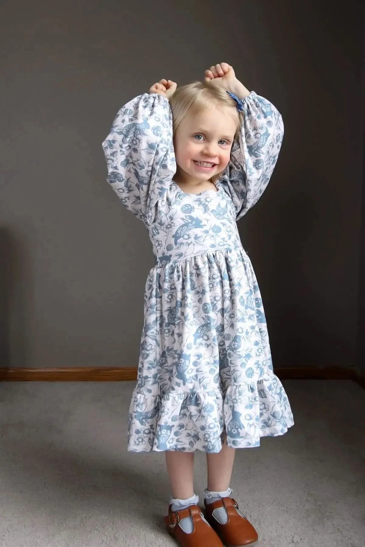 A young girl in a blue and white bunny bramble dress with puffed sleeves.