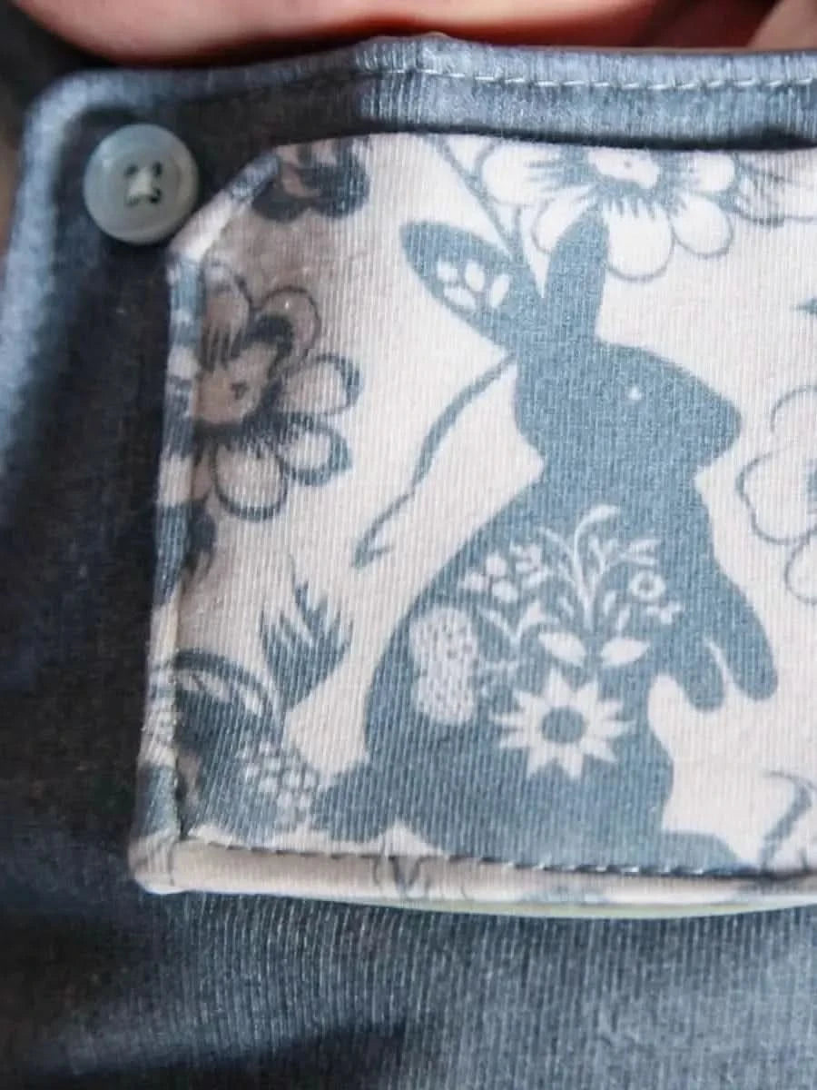 Close-up of a blue fabric with a white bunny and floral pattern.