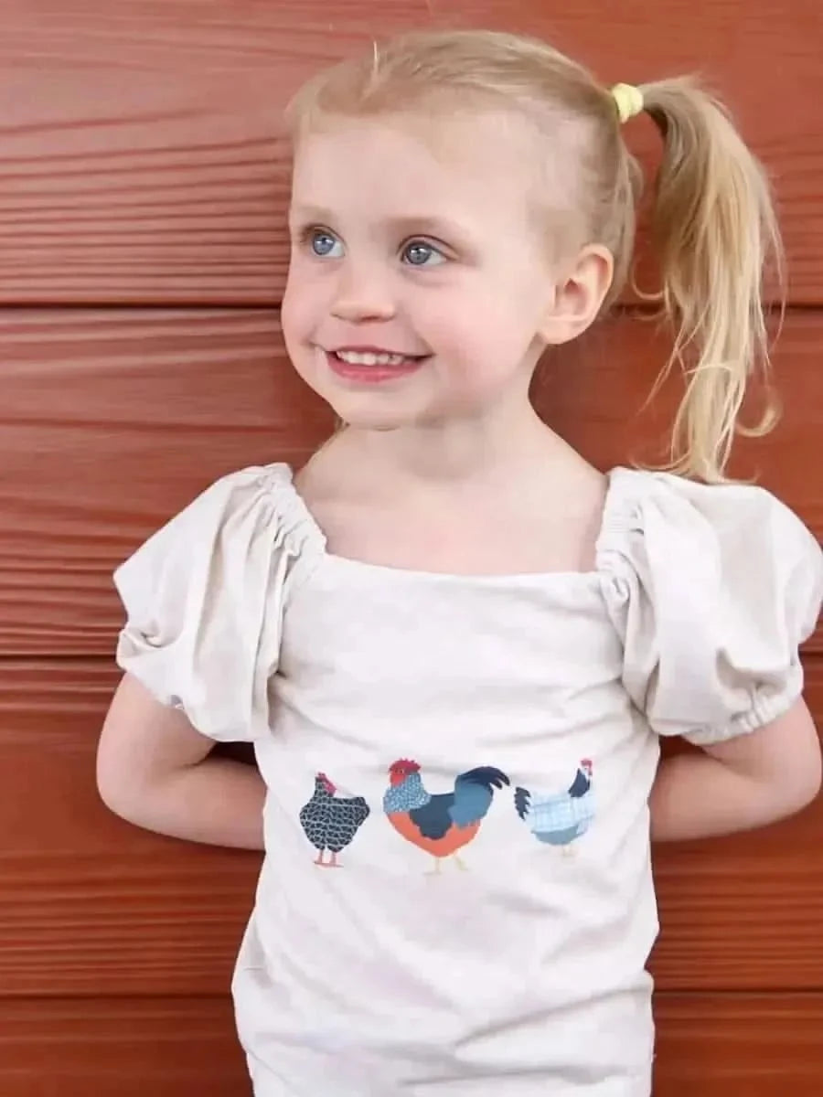 Fabric panel featuring colorful patchwork chicken designs on beige background.