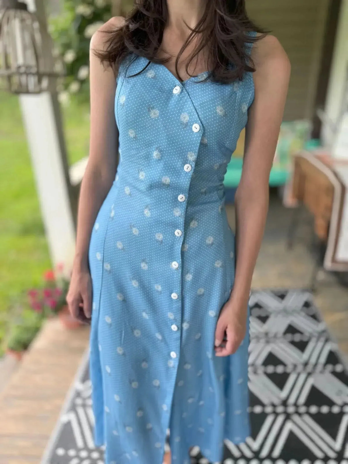 A person models a blue dress with white polka dots and floral patterns.