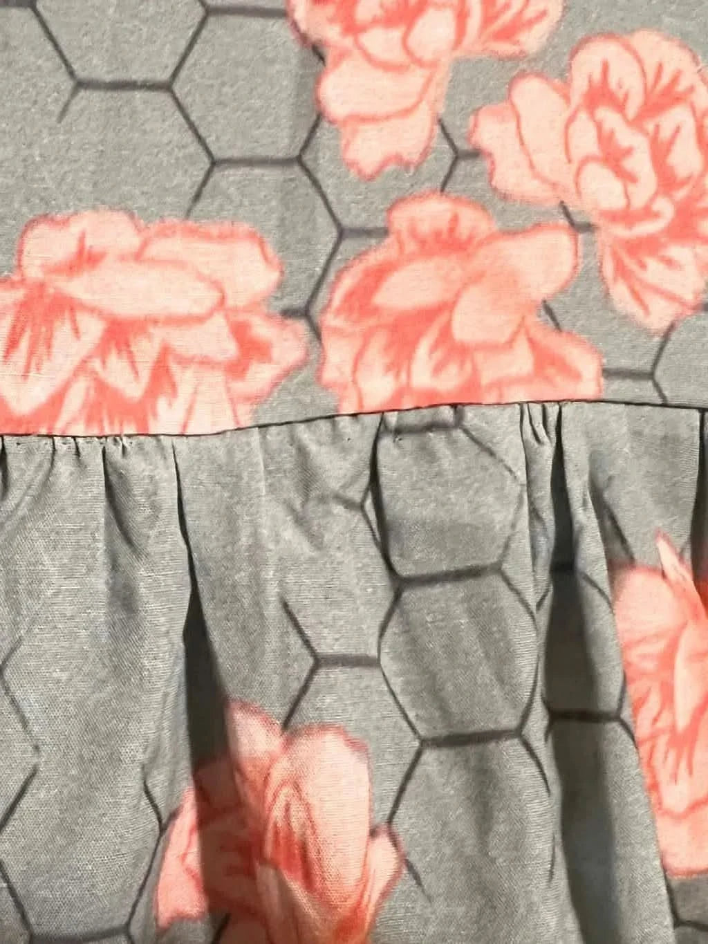 Gray fabric with a honeycomb pattern, pink flowers, and a ruffled seam.
