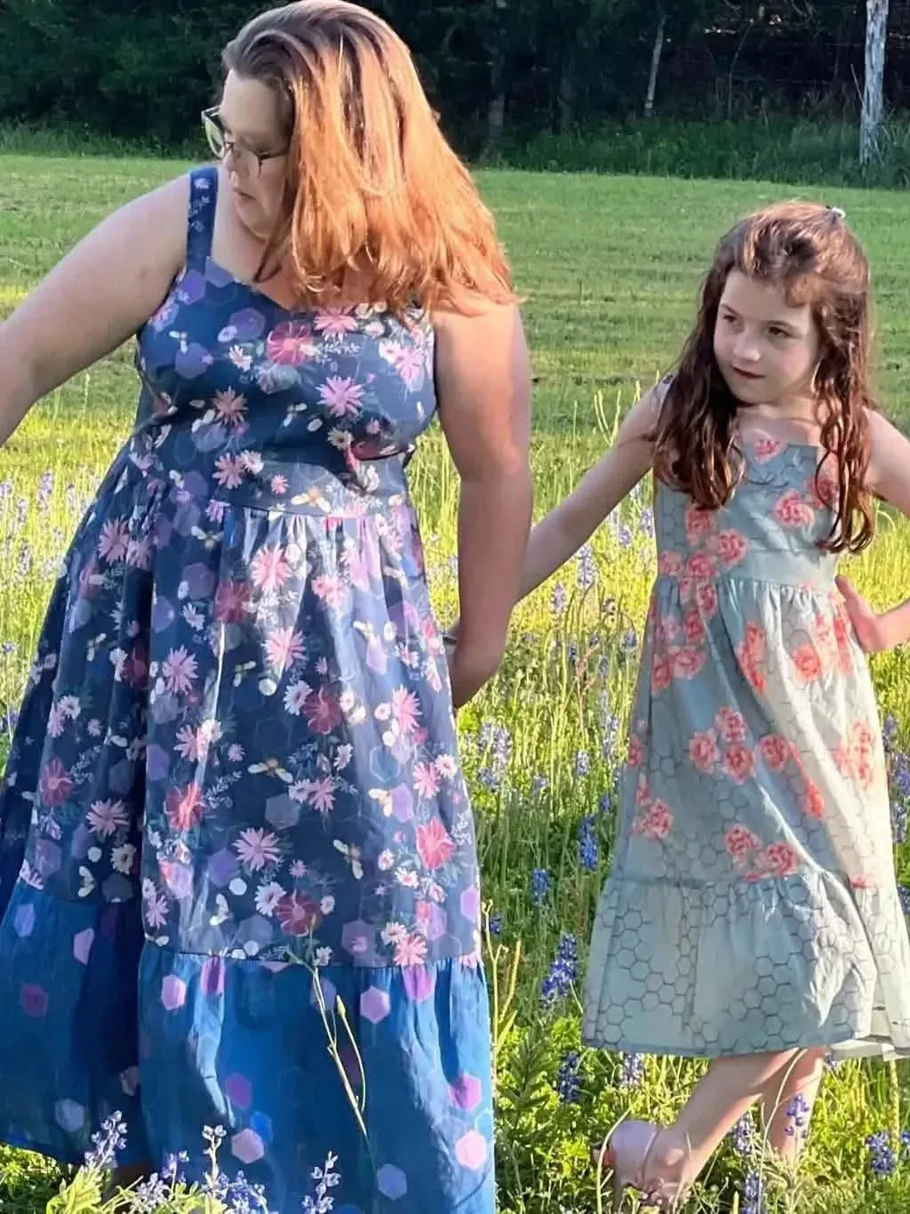 Purple fabric with garden bees print, shown in a flowing dress on a woman and girl in a field.