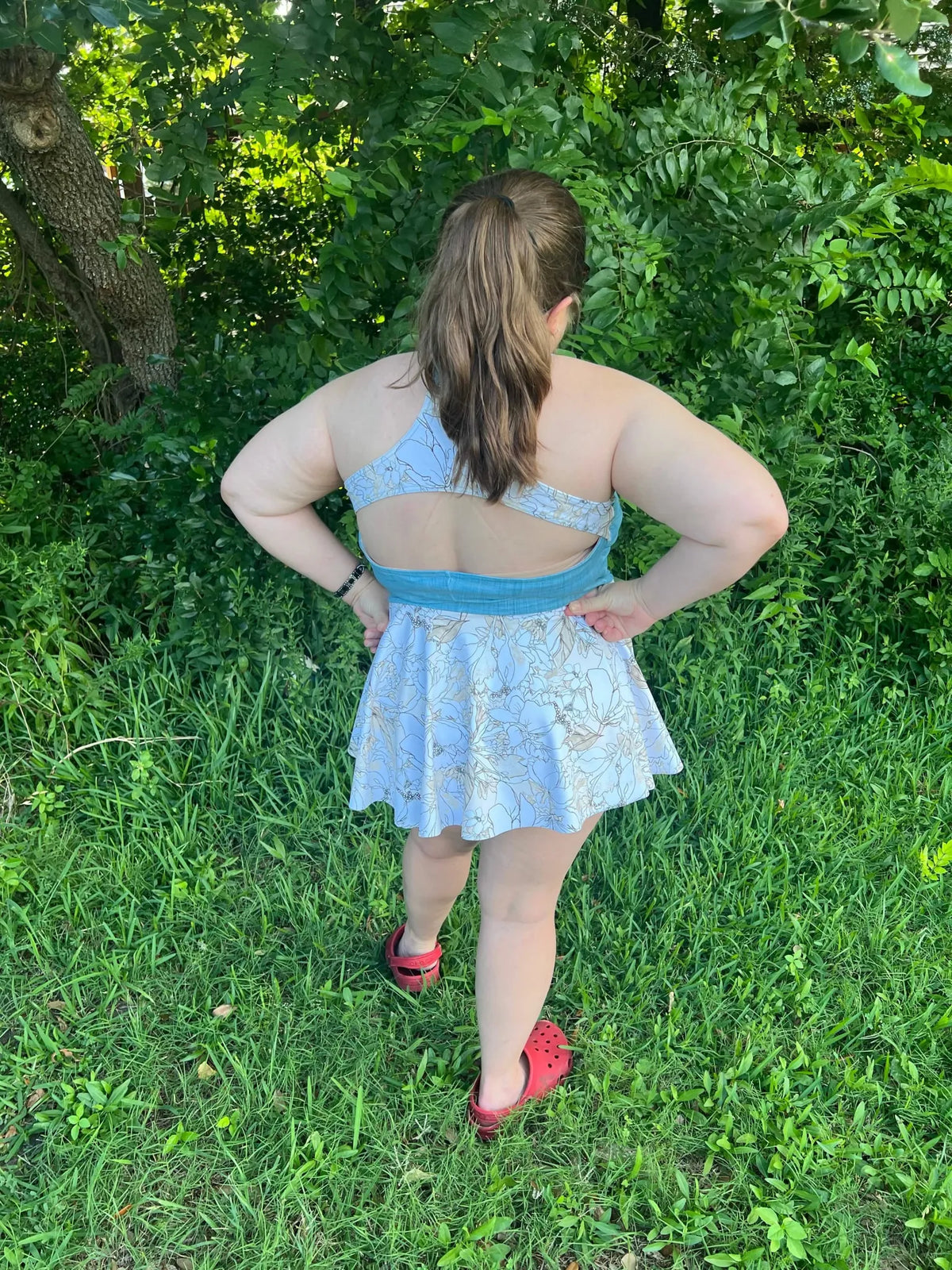 A person from behind wearing a light blue floral dress with a cutout back.