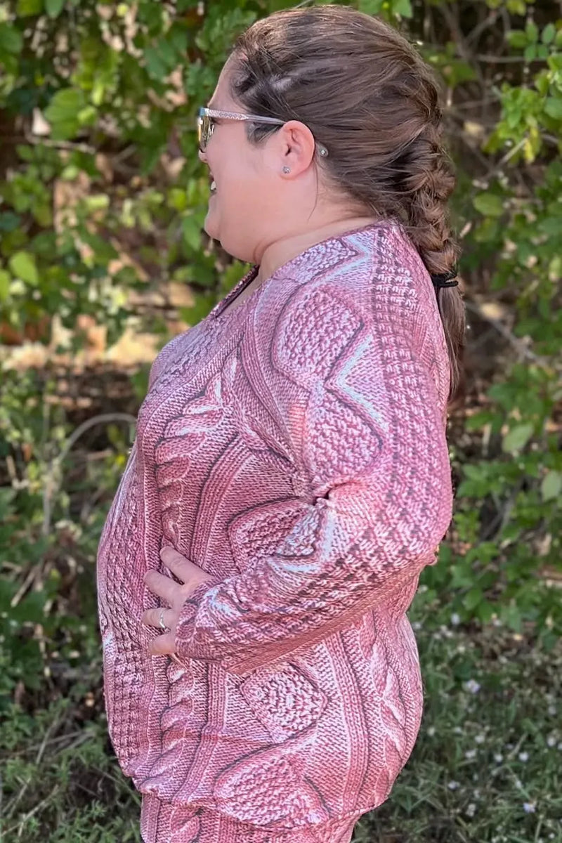 A person wearing a rose cable knit patterned top with a braided ponytail.