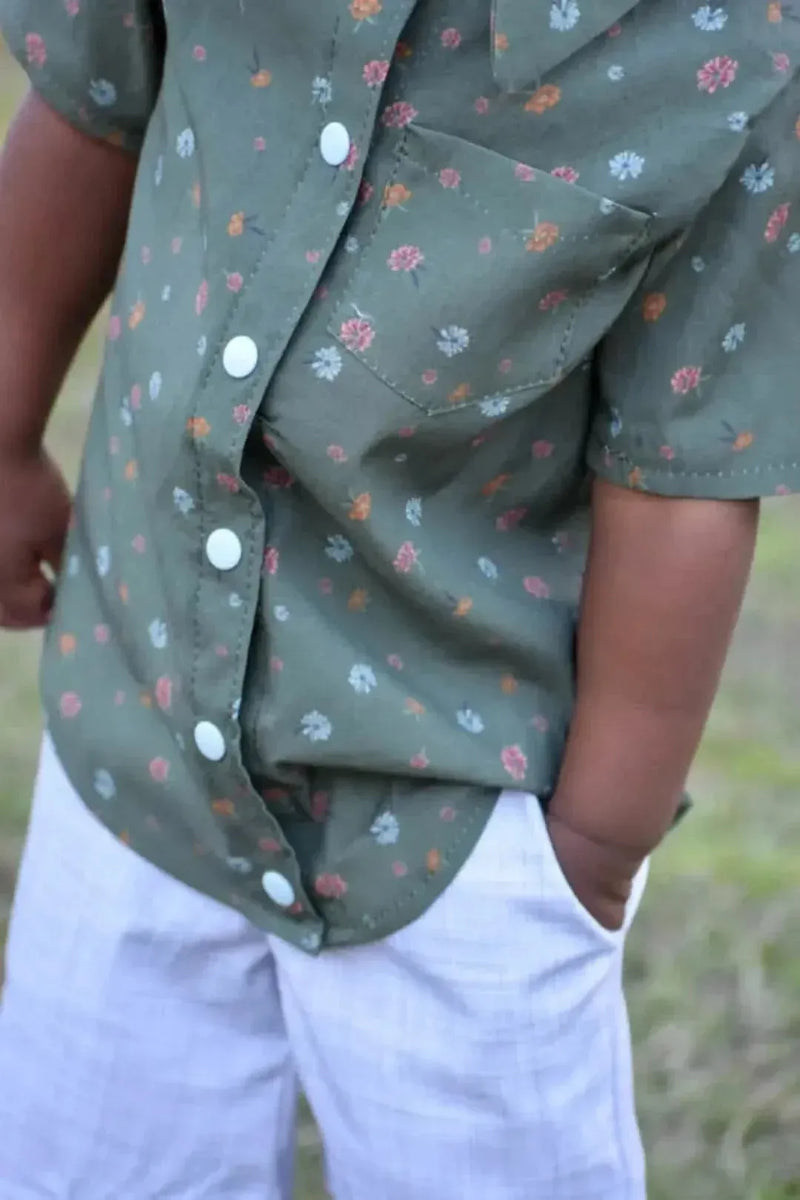 Olive ditsy floral fabric with small pink blooms on green background.