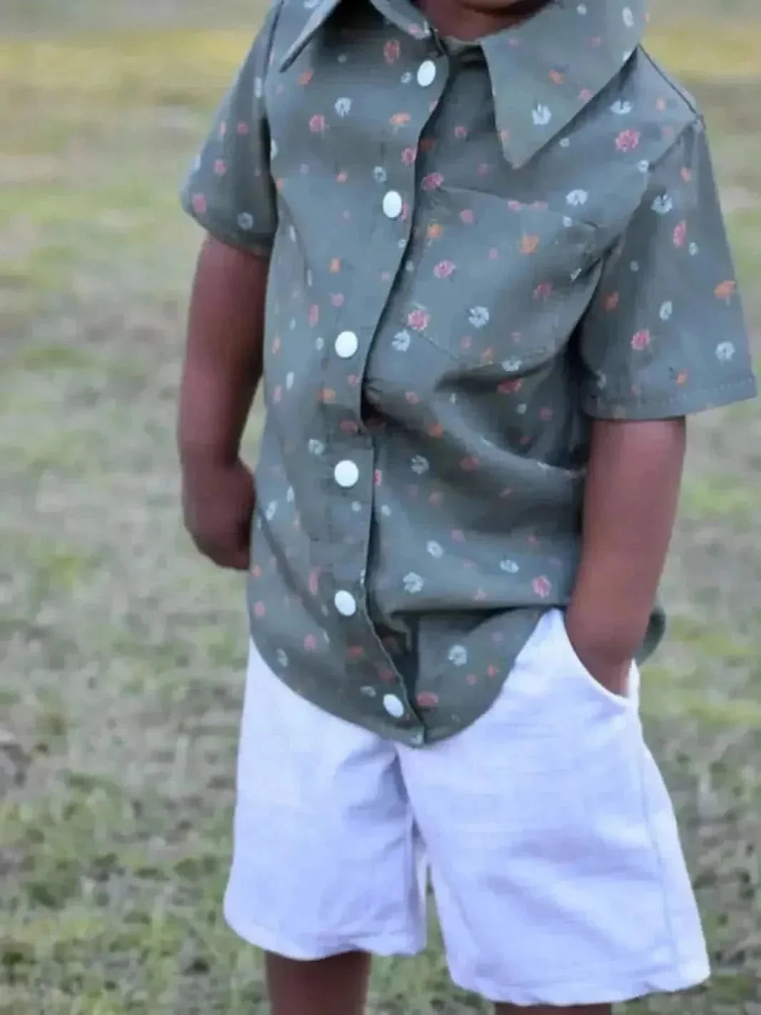 Olive ditsy floral fabric with bitty blooms pattern, shown in a child's button-up shirt.