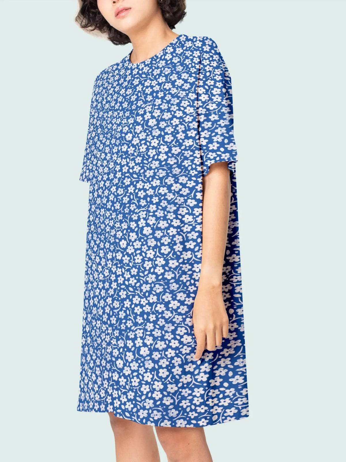 A woman wears a blue floral dress with short sleeves.