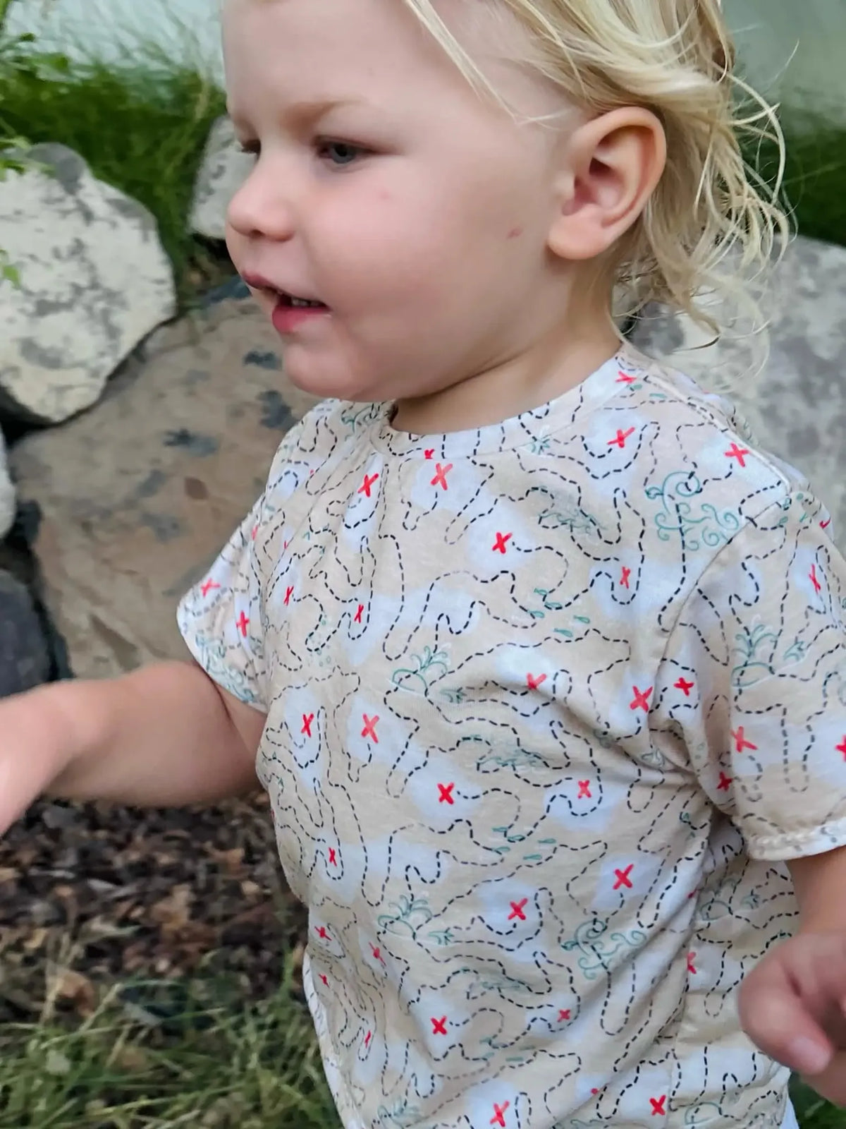 A child wears a shirt with a "Buried Treasure" map pattern.