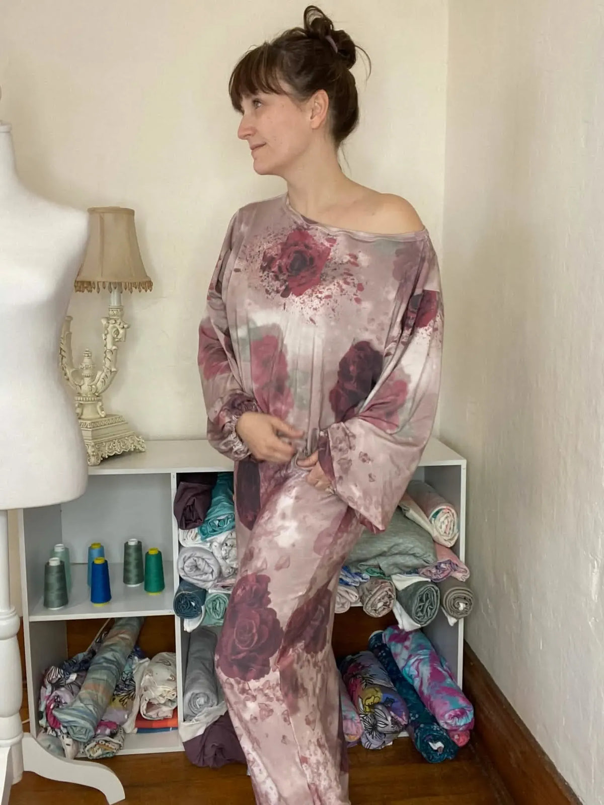 A woman models a long, loose-fitting dress with a shattered rose pattern.