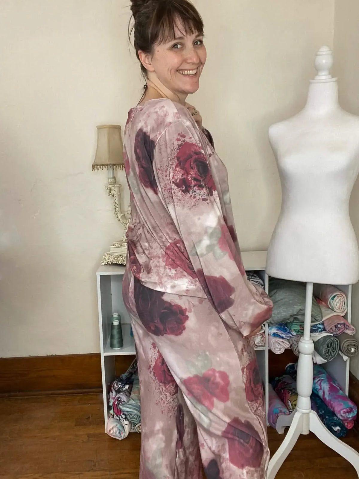 Woman wearing a pink and red floral print long-sleeved top and matching pants.