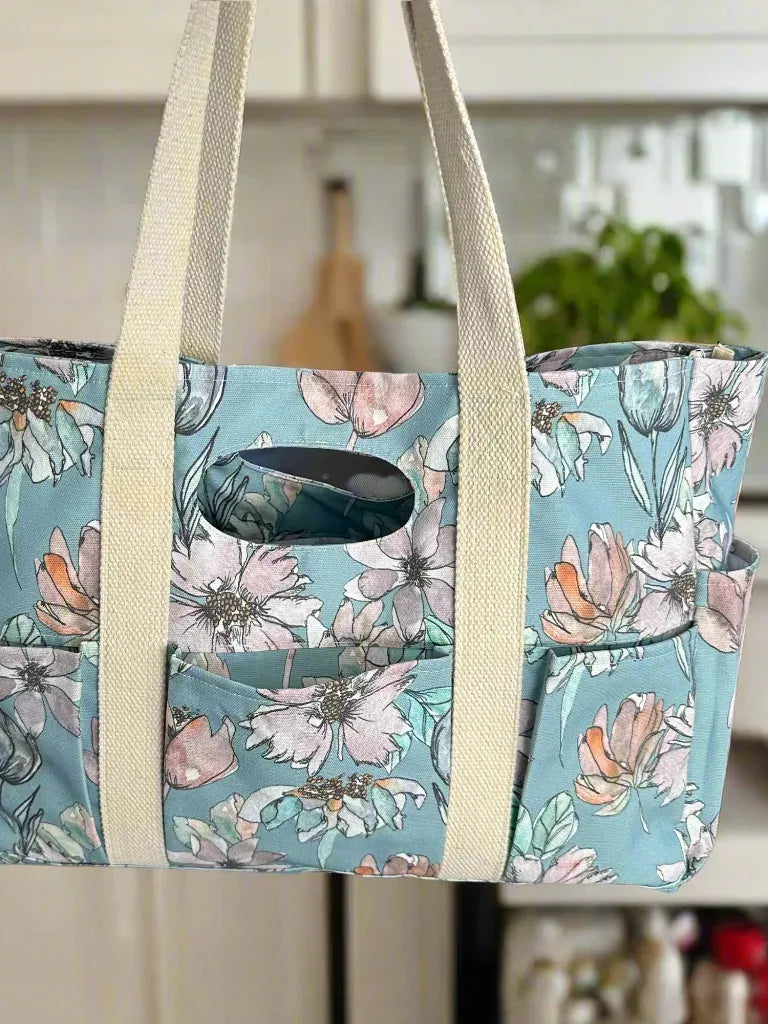 A floral tote bag with multiple pockets and cream-colored straps.