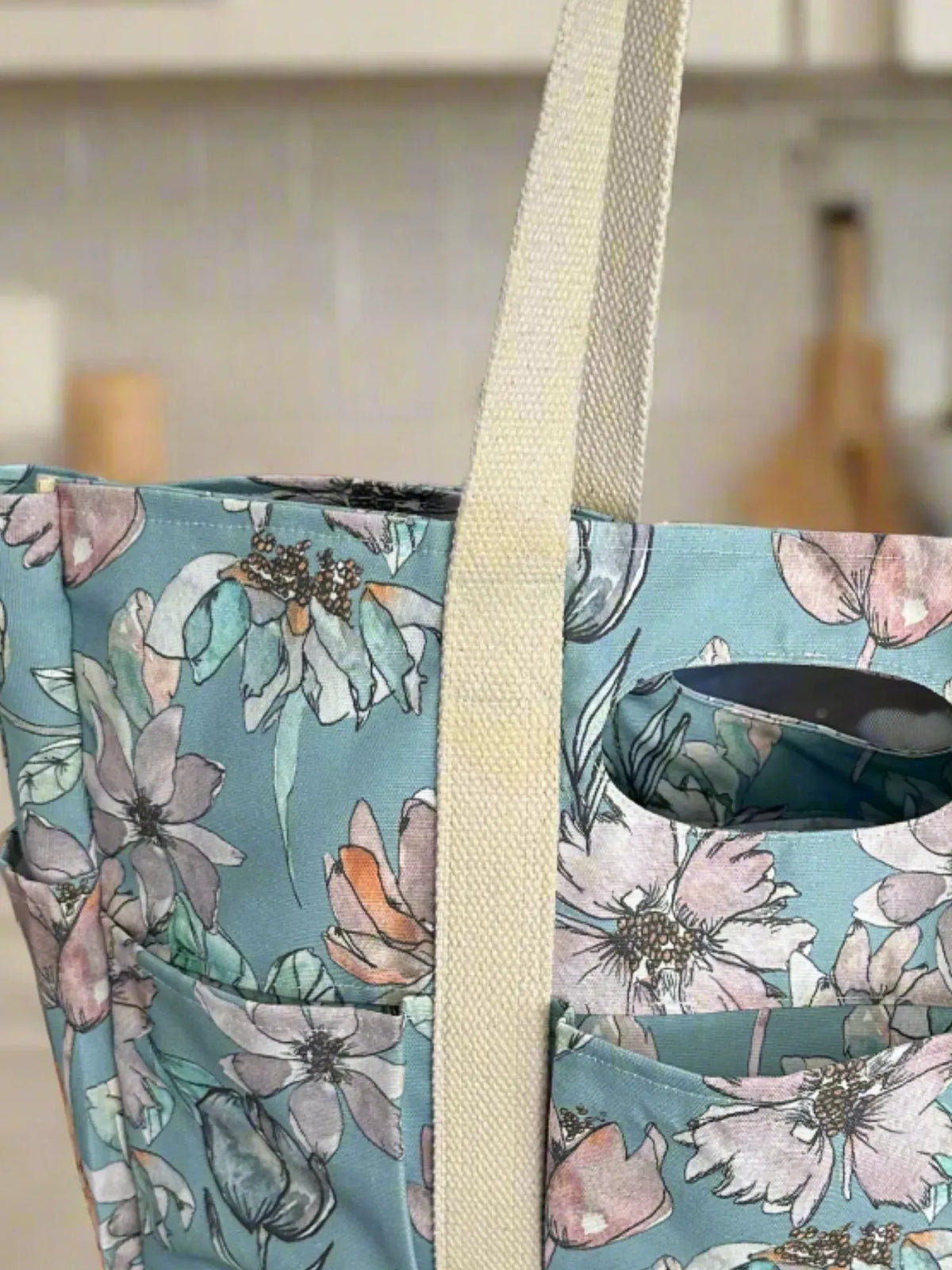 A floral tote bag with light blue fabric and cream-colored straps.