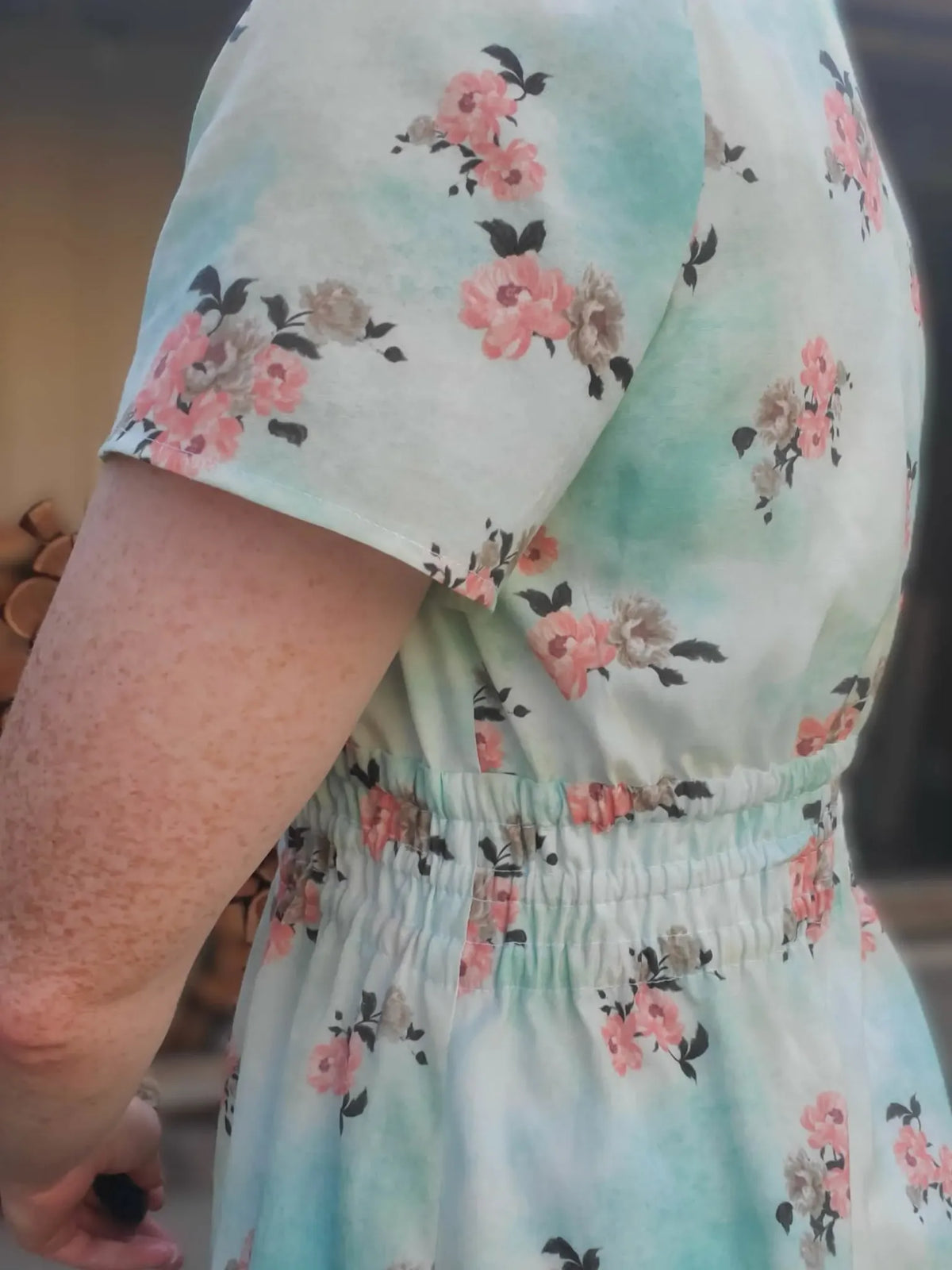 A person wearing a dress with a light blue and pink floral pattern.