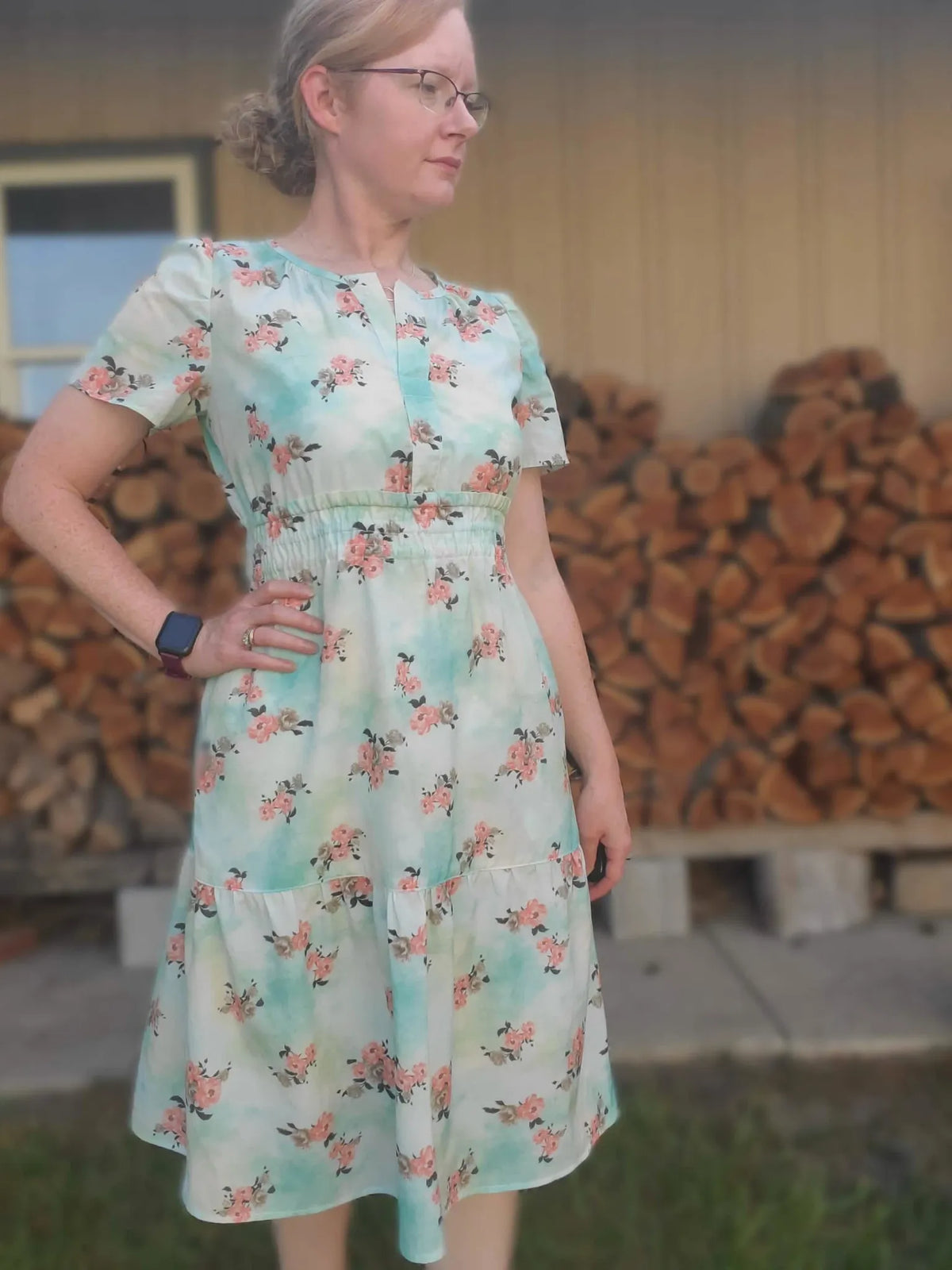 A woman wears a floral dress with a light blue and white background.
