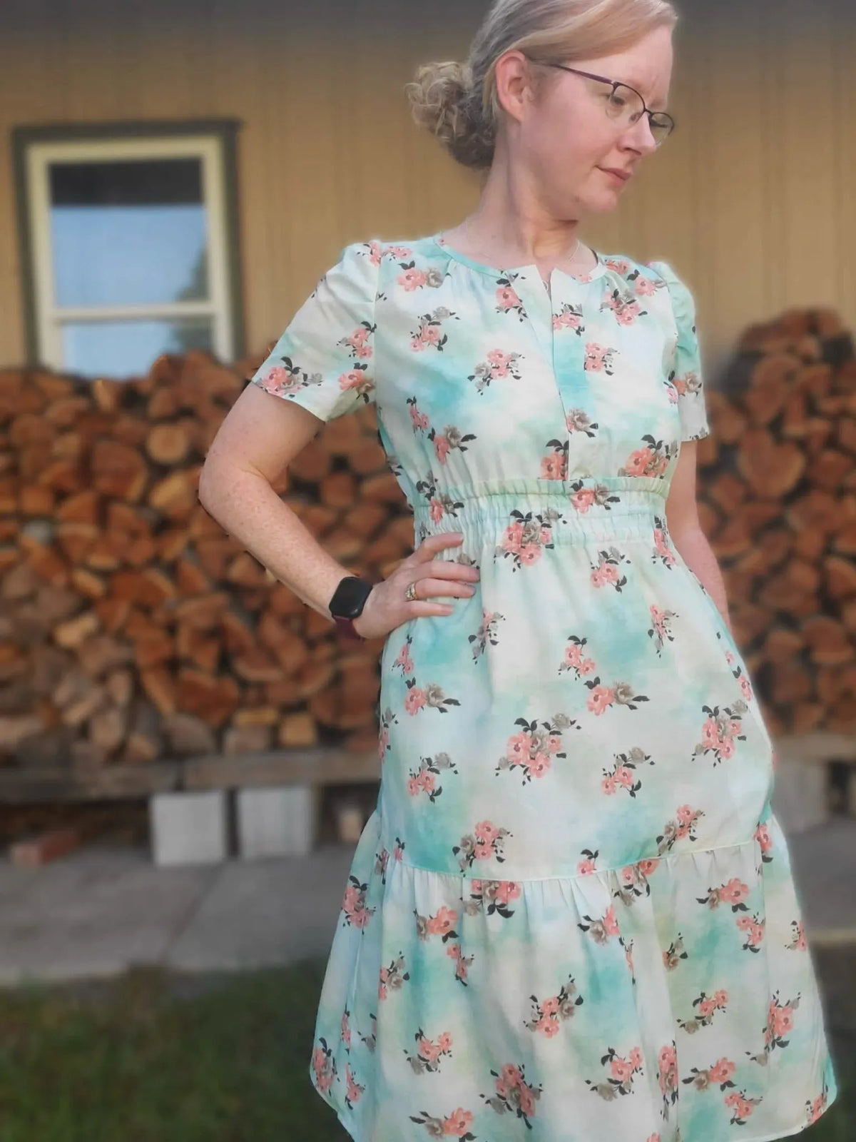 A woman wears a floral dress with a light blue and white tie-dye pattern.