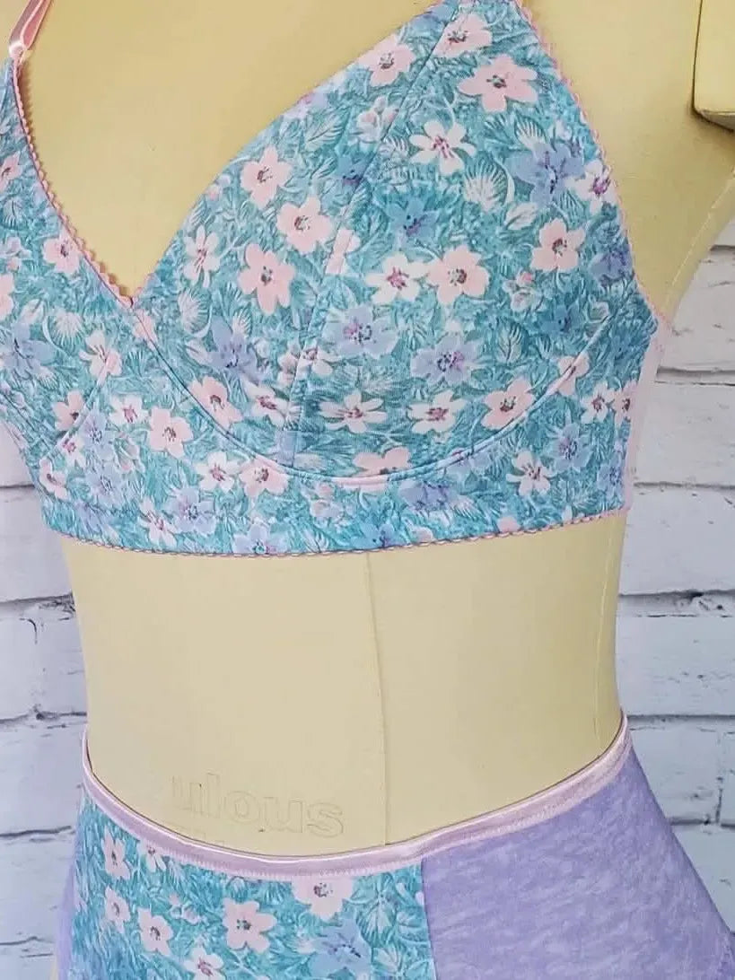 A floral bra and underwear set on a mannequin against a white brick wall.