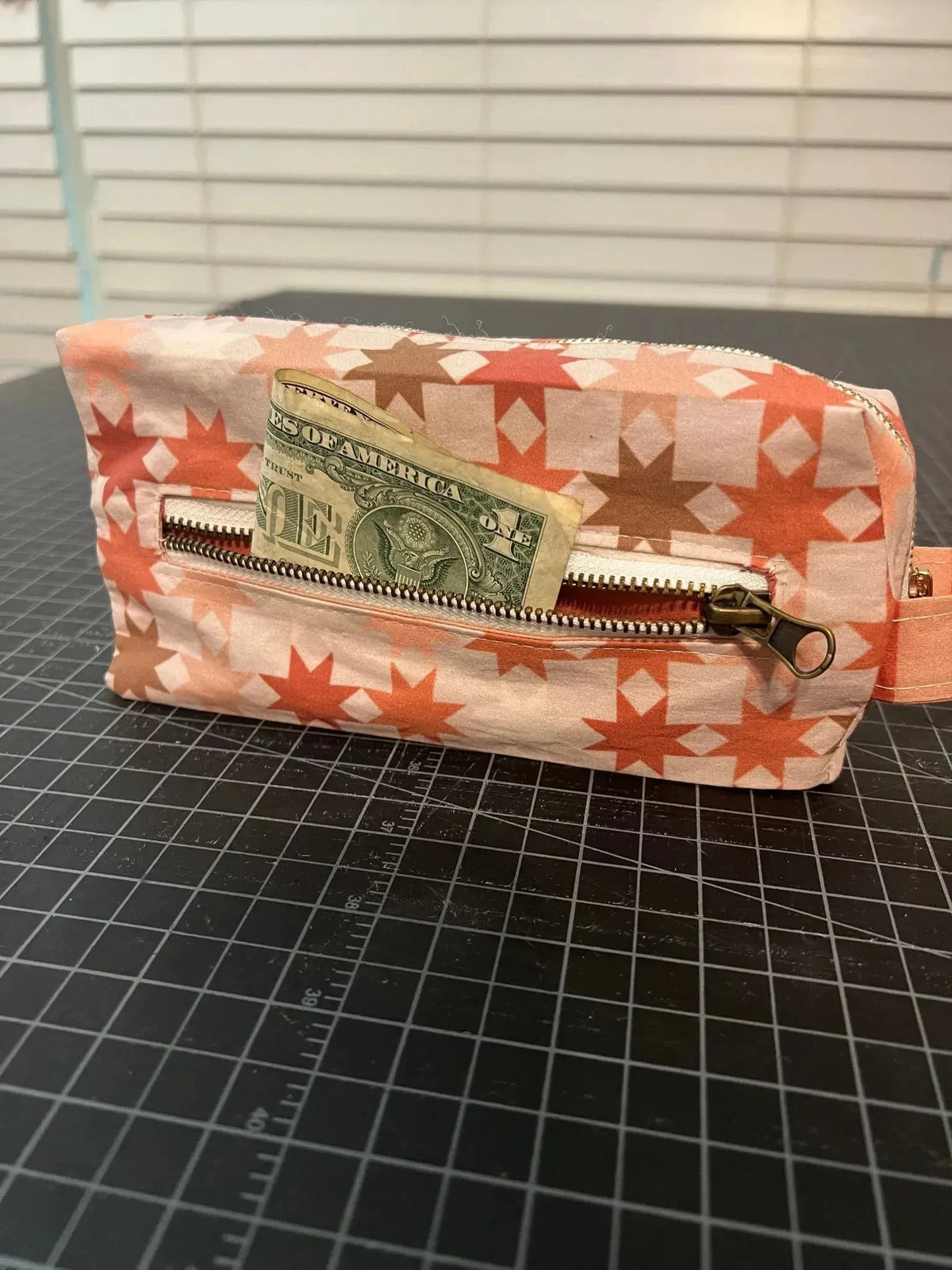 Orange geometric southwest print fabric with star patterns, shown as a small pouch holding cash.