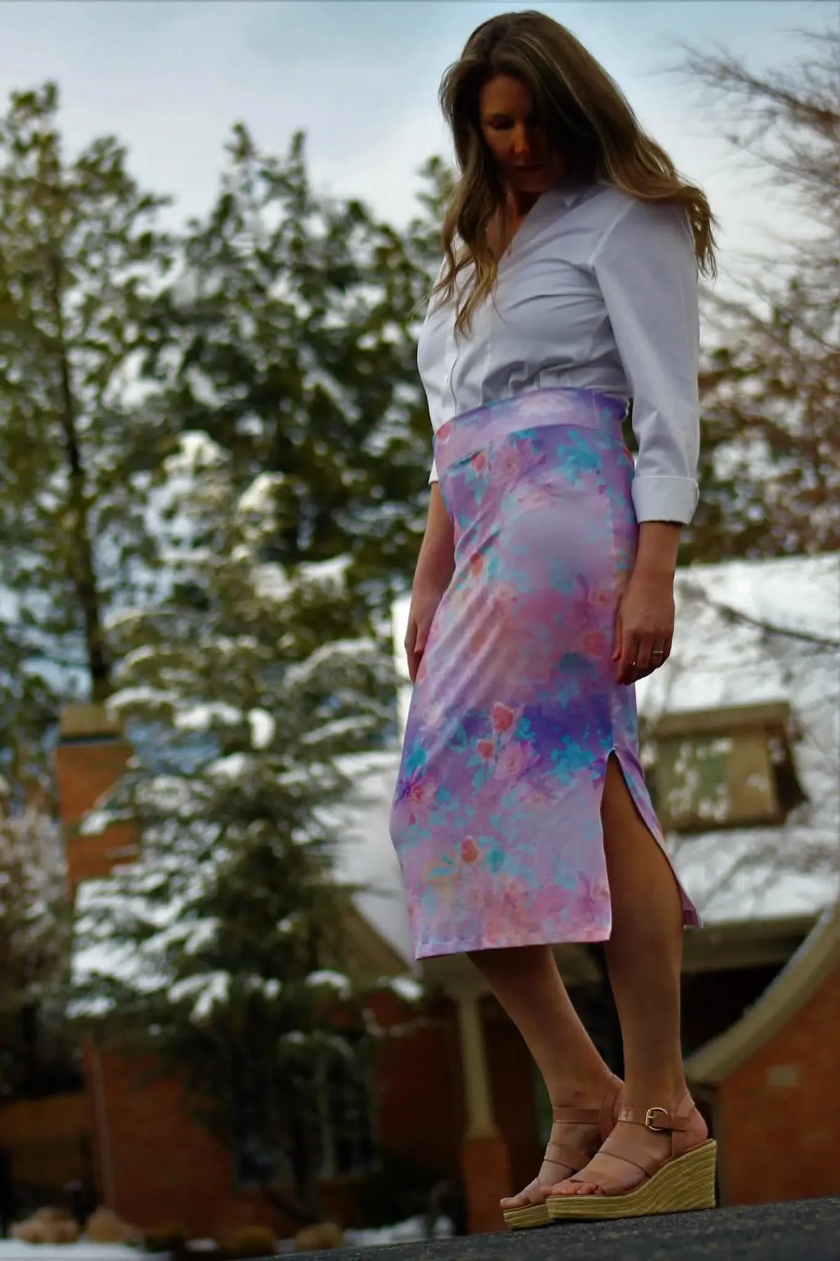 Woman in a white shirt and a purple floral skirt with a side slit.