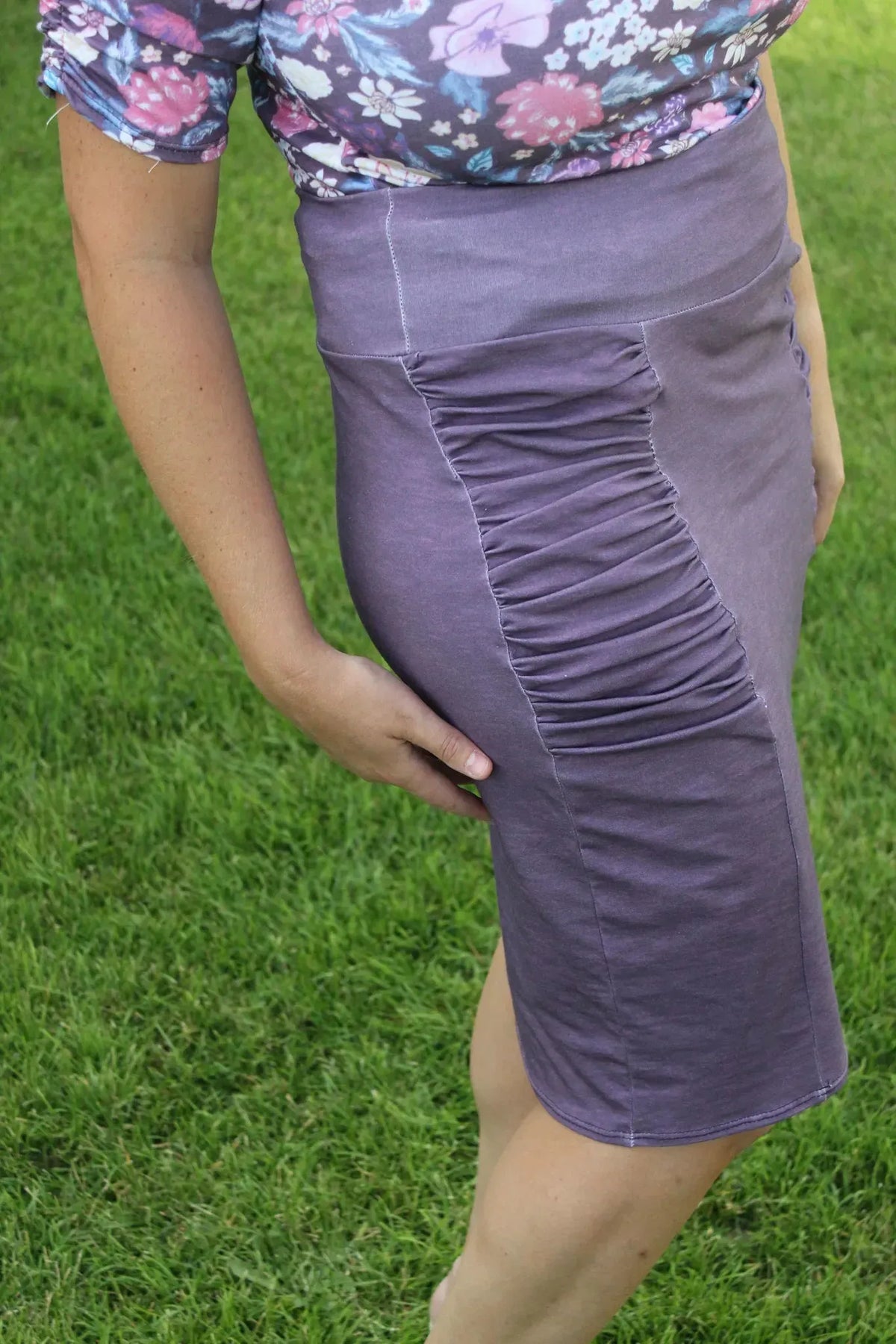 A person models a maroon heather ruched skirt with a floral top.