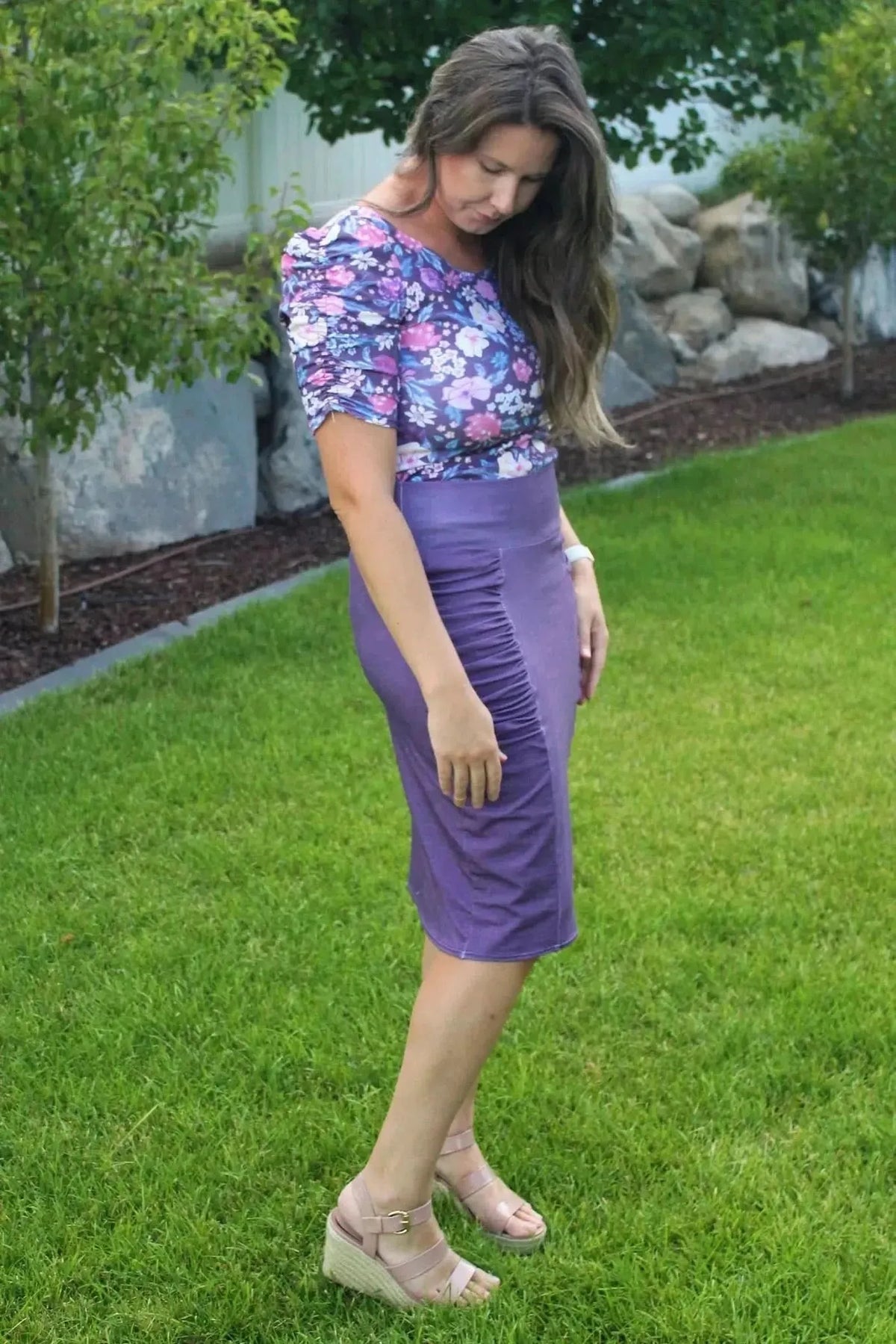 Woman modeling a maroon floral print blouse and matching skirt in a garden setting.