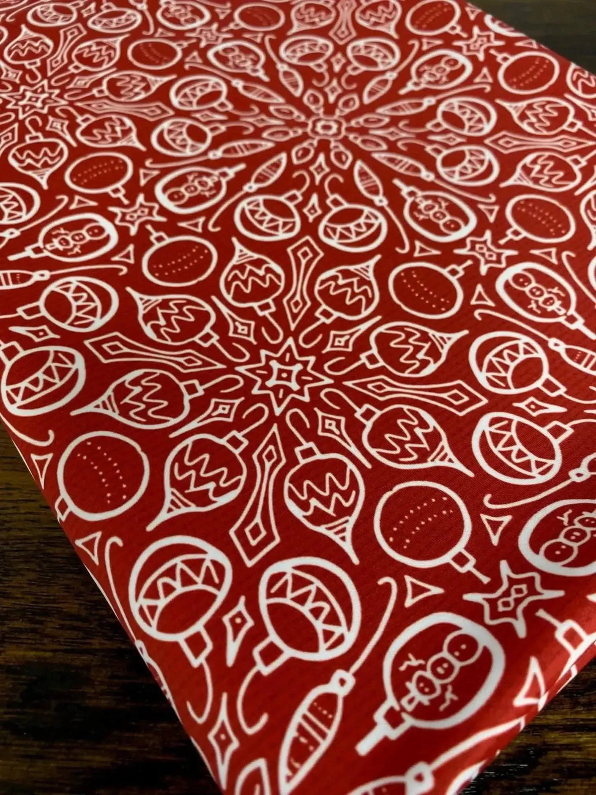 Red fabric with white Christmas ornaments and snowflakes in a festive pattern.
