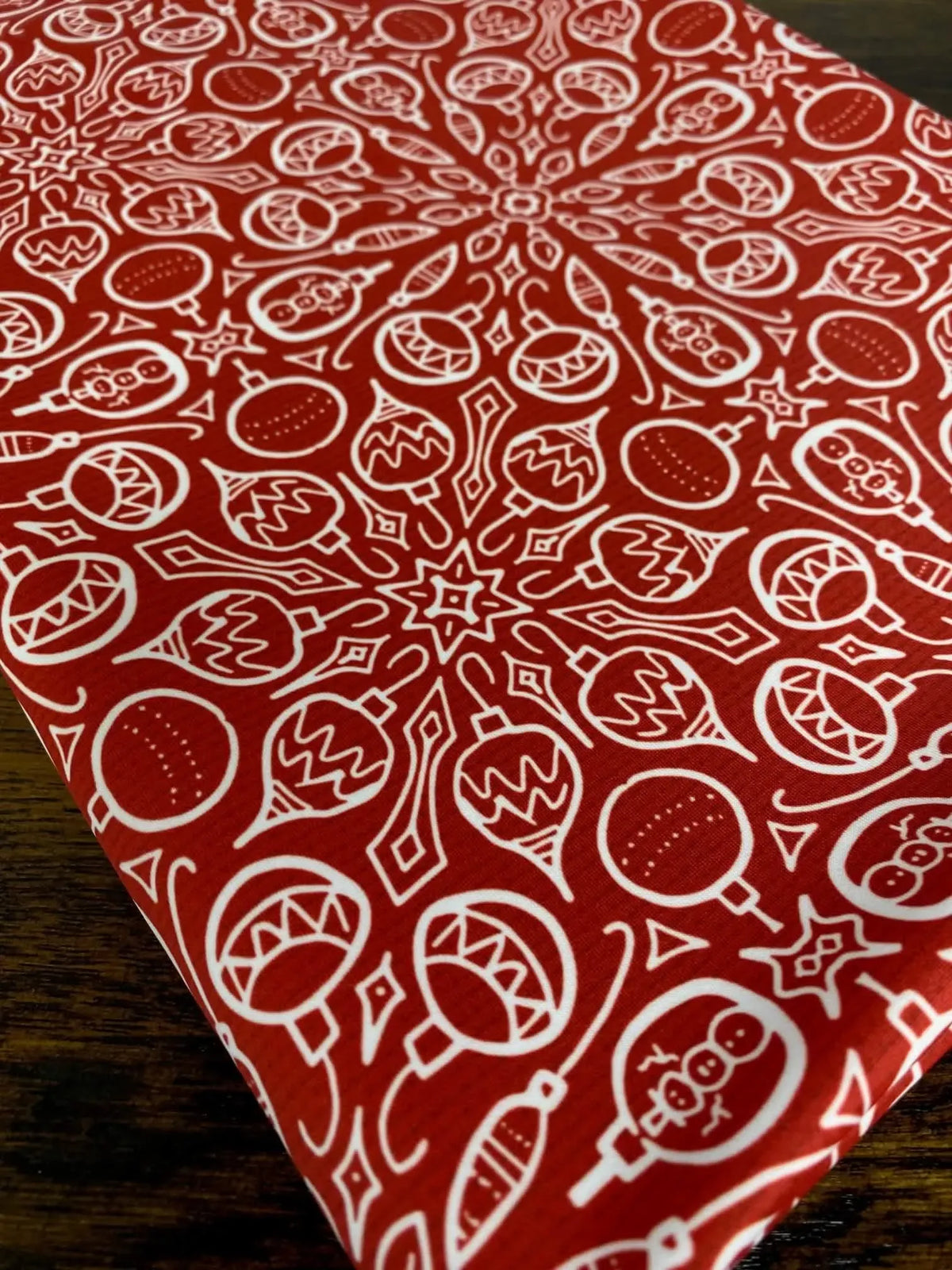 Red fabric with a white Christmas ornament pattern.