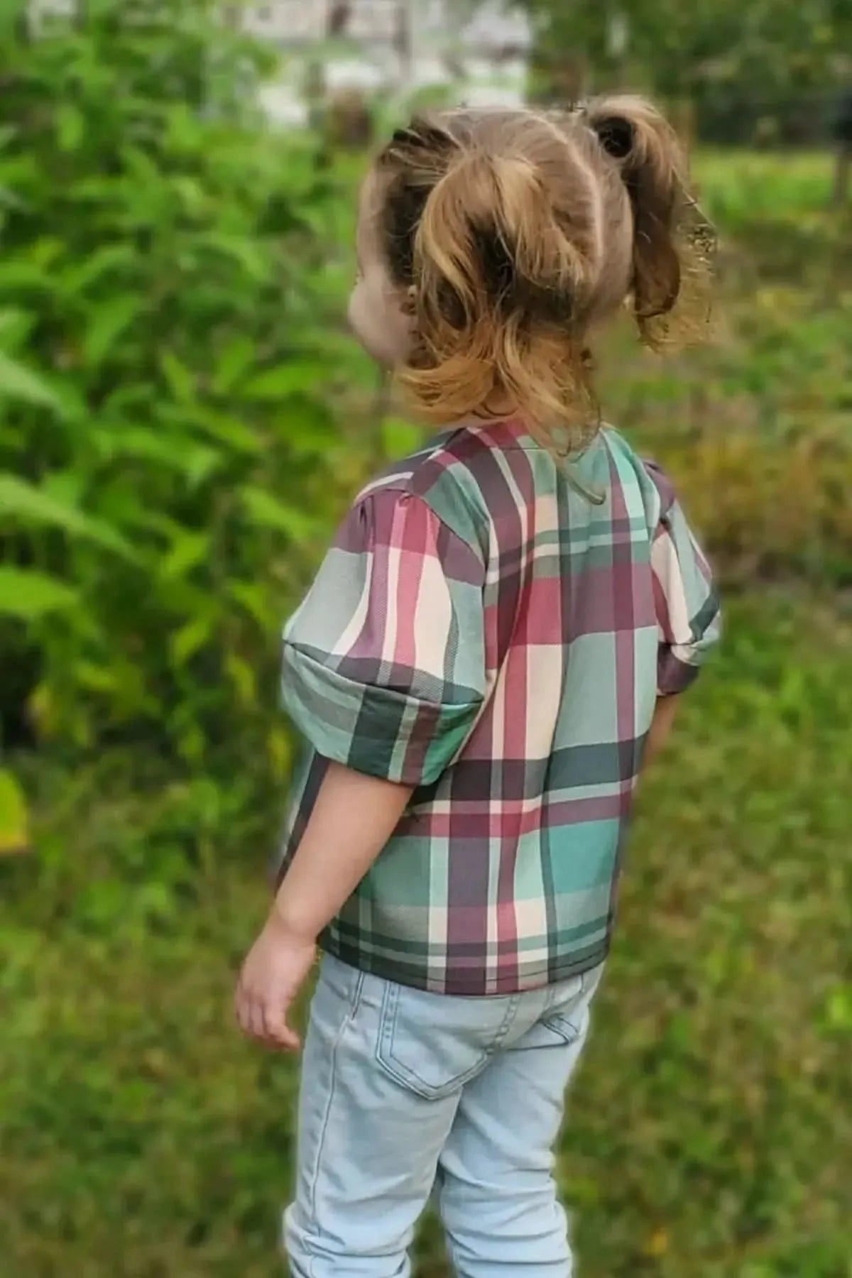 Teal and purple plaid holiday fabric with light Christmas print, shown on a child's shirt.