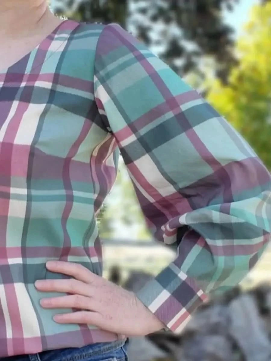 A person wears a plaid shirt with teal, purple, pink, and white colors.