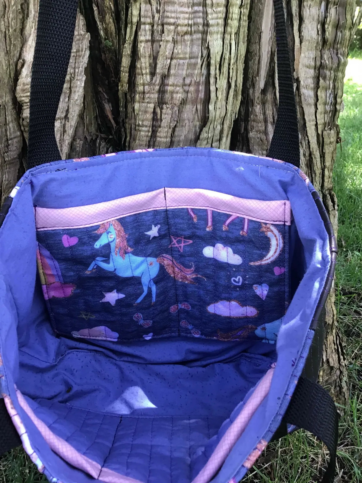 Navy unicorn fabric tote bag with purple lining and black straps.