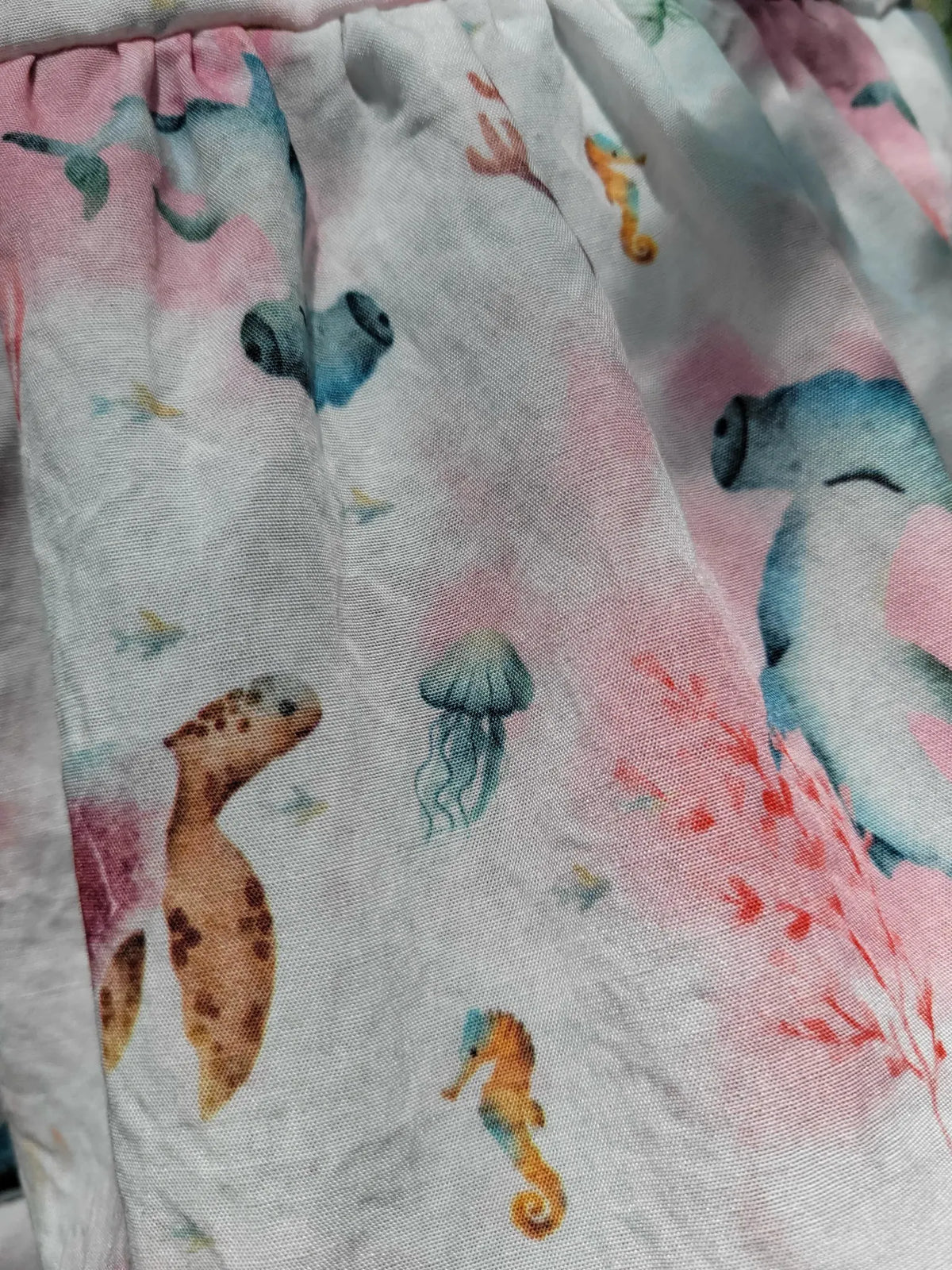 Fabric with an "Under The Sea" pattern featuring marine life and pink accents.