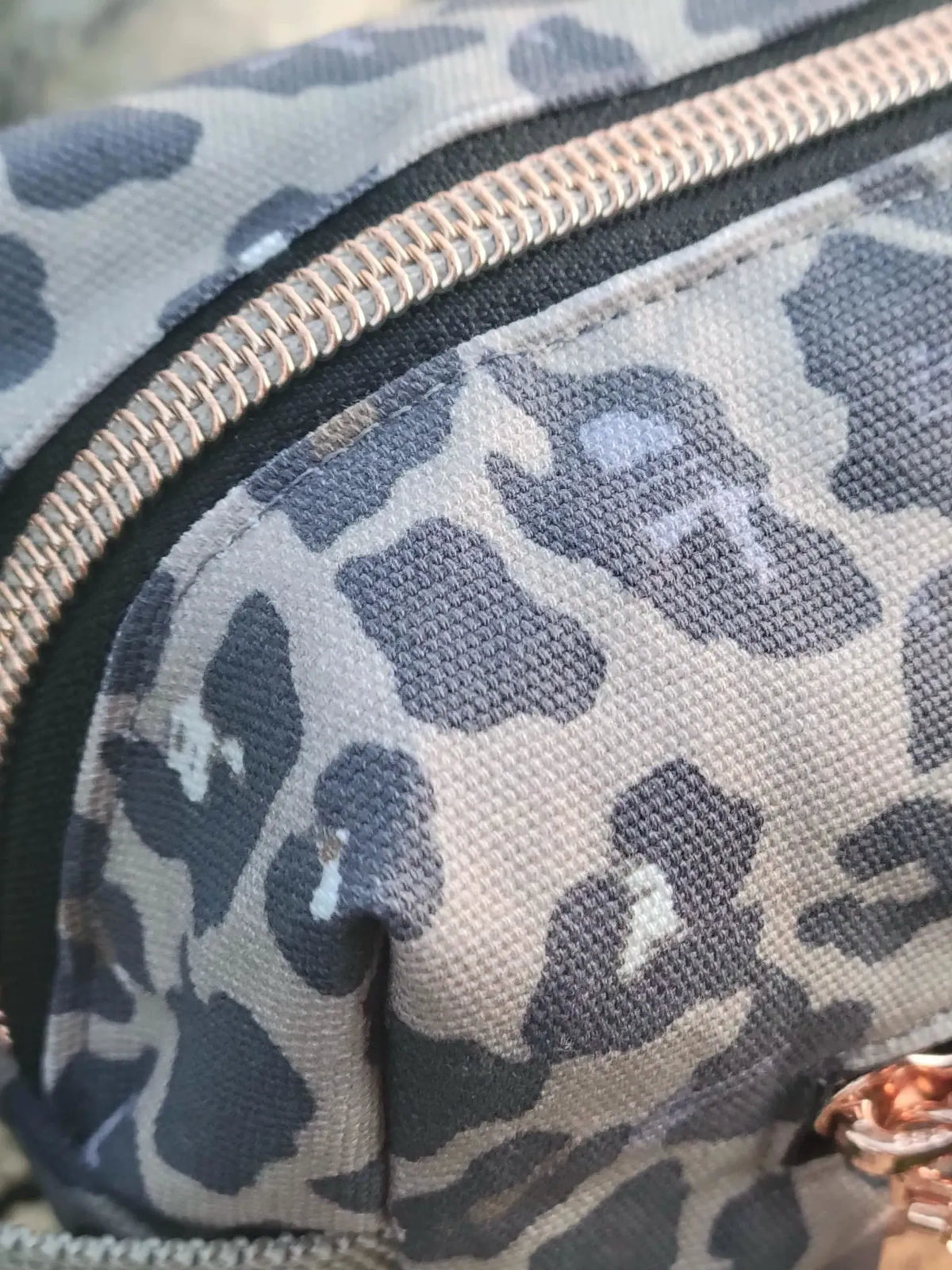 A close-up of a leopard print fabric with rose gold zippers.