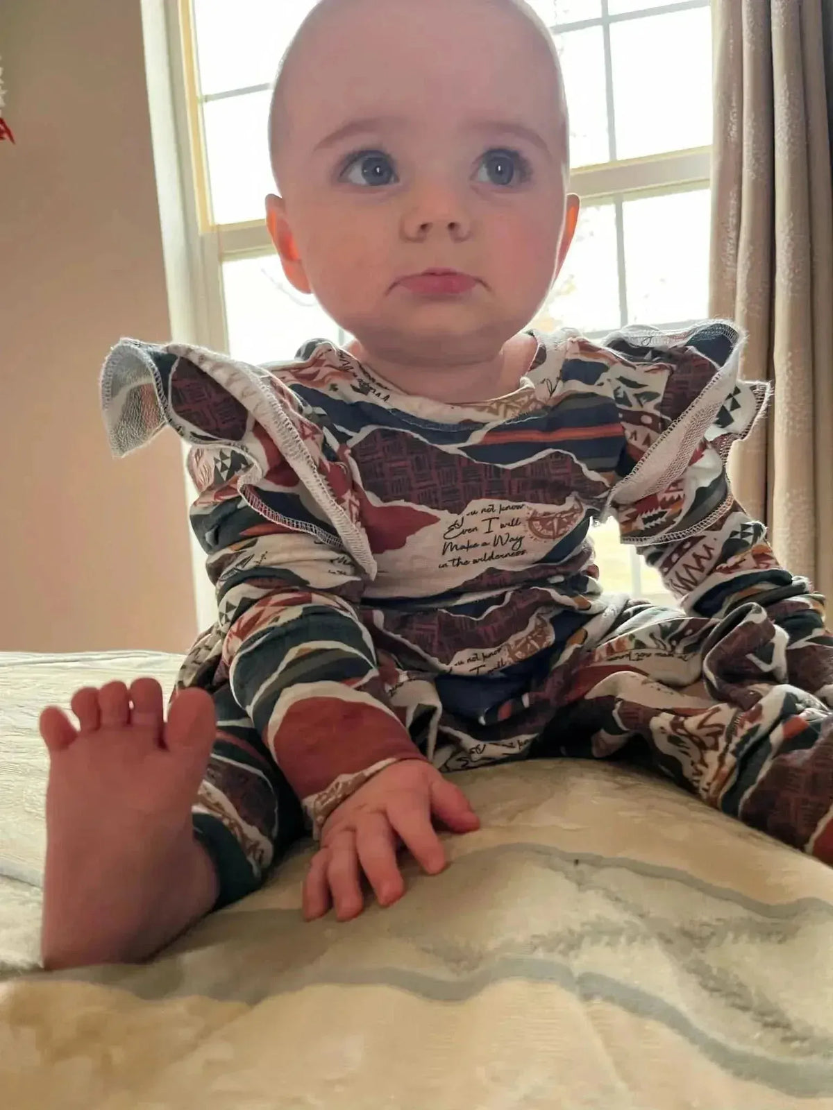 Baby onesie made from WayMaker Fabrics faith-based print with camouflage pattern and ruffled shoulders.