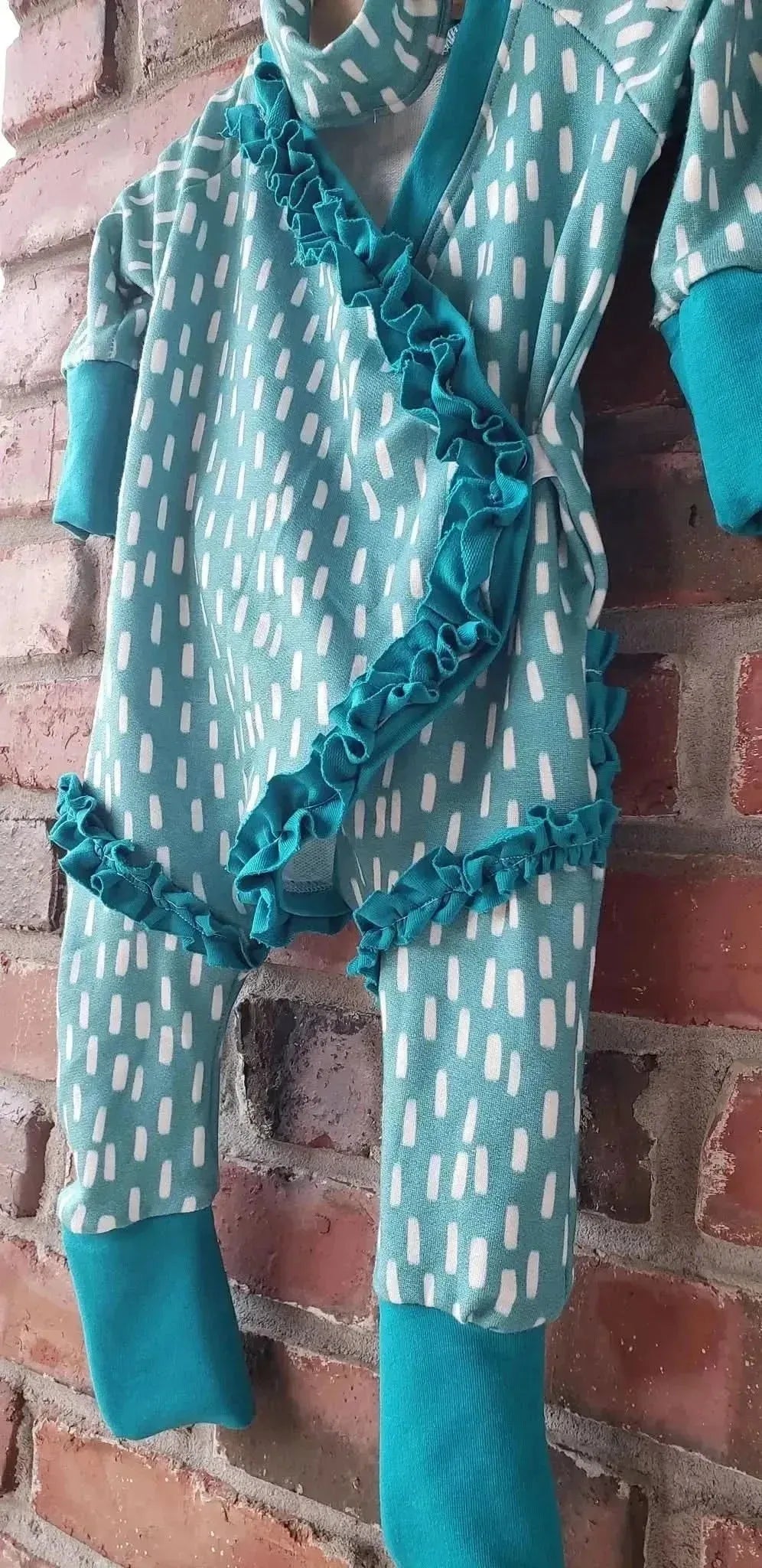 Blue dash pattern print fabric in light teal with white stripes, shown as a sewn baby romper.