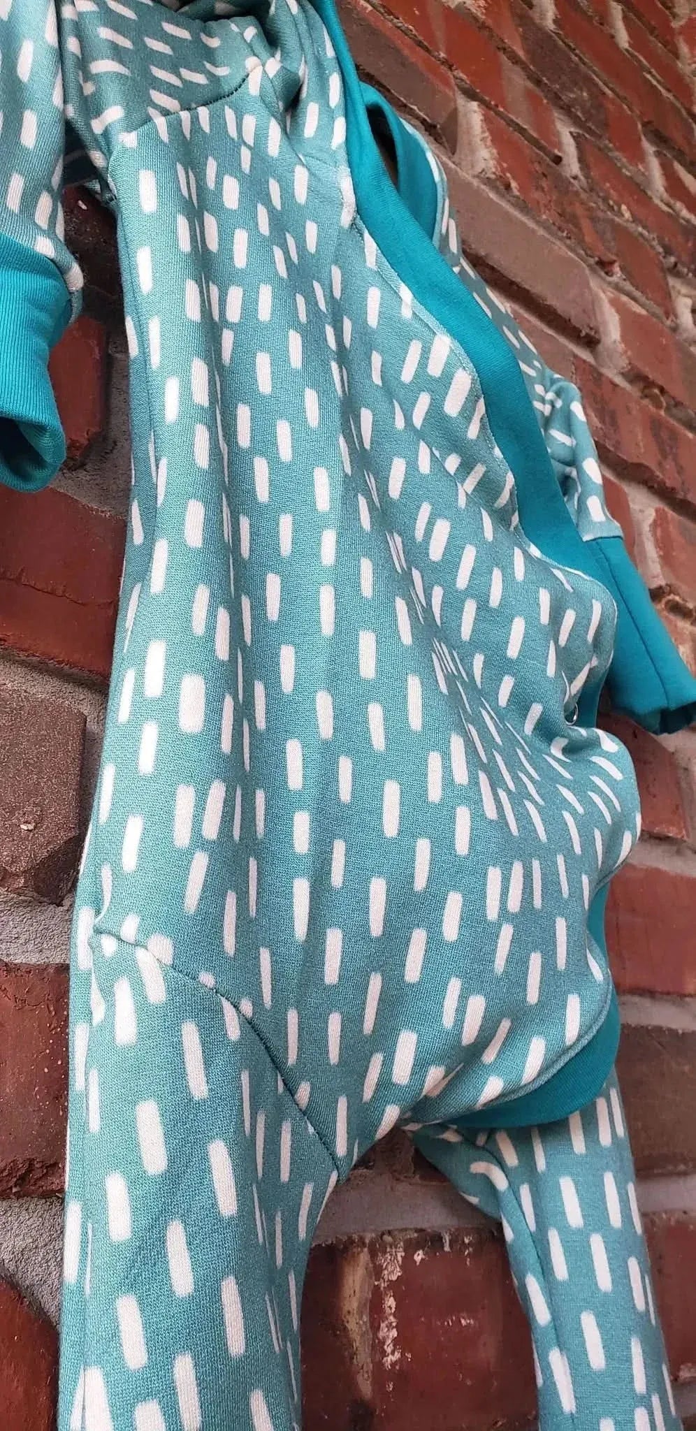 Blue fabric with white dash patterns hangs against a brick wall.