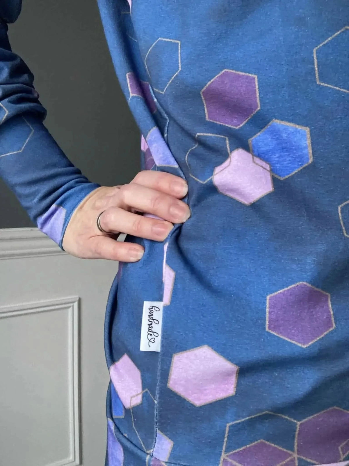 A person wearing a blue garment with purple and blue geometric patterns.