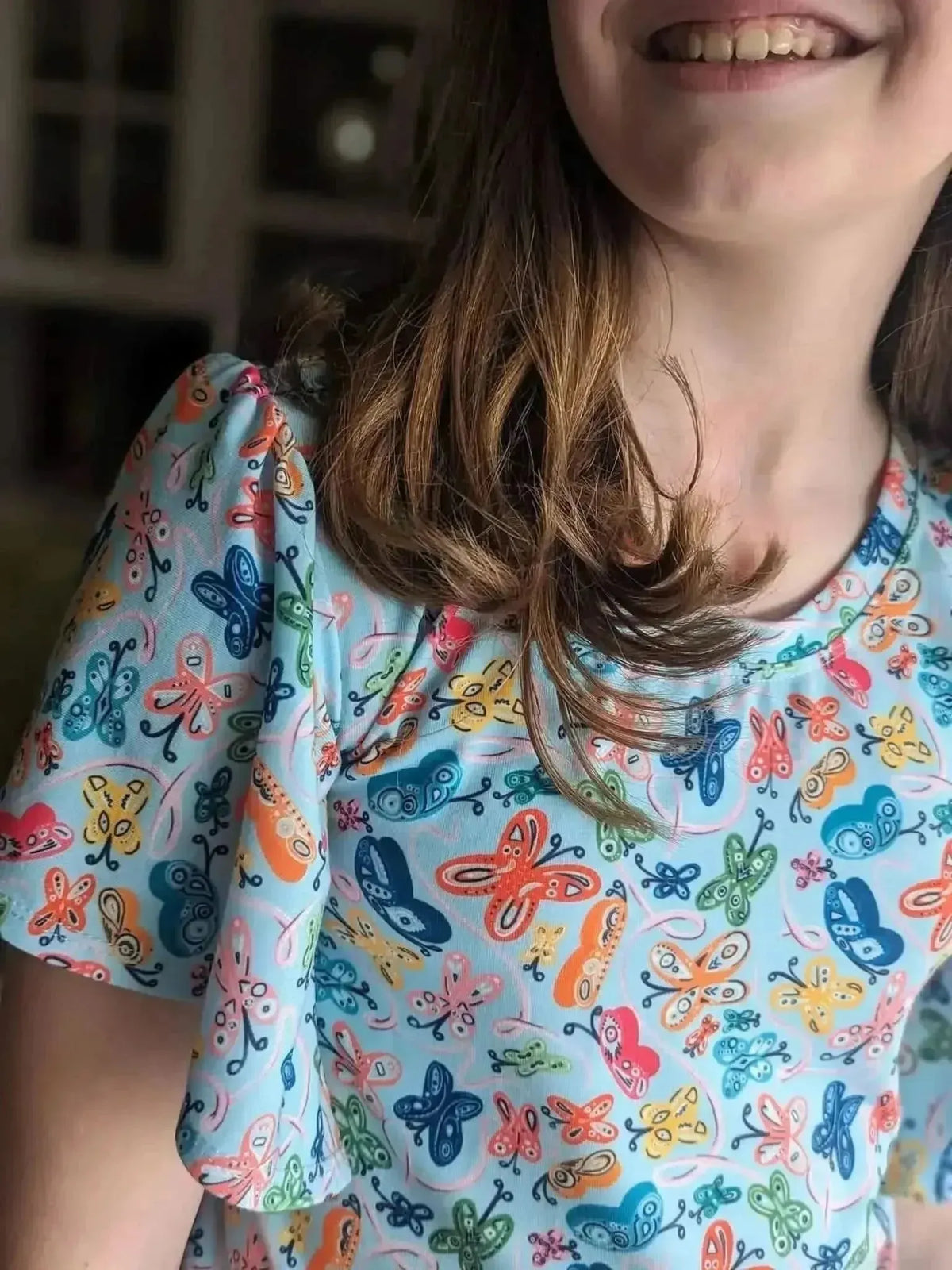 Light blue fabric with vibrant painted butterfly print in multiple colors.