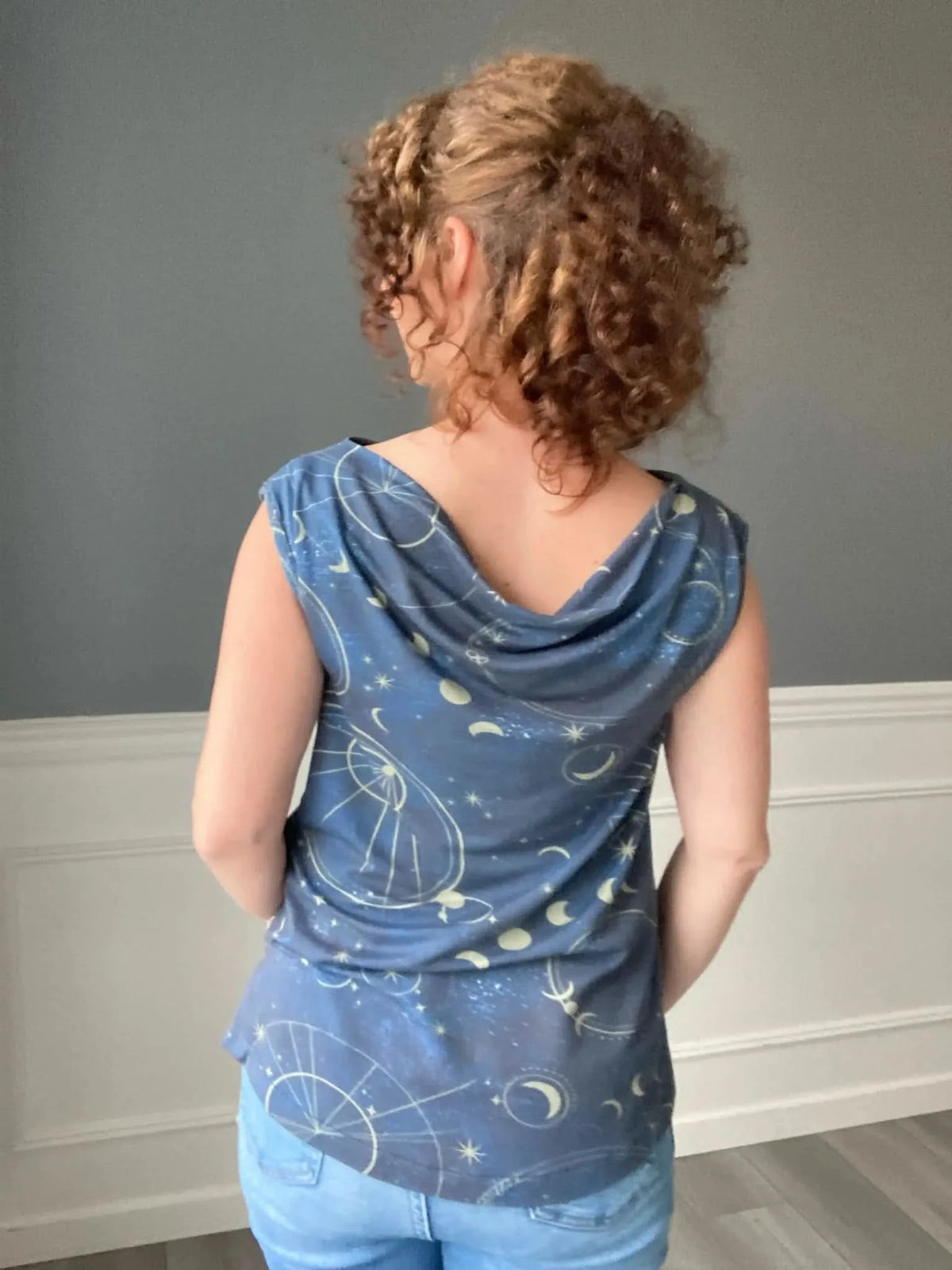 A person from behind wearing a blue top with a celestial pattern.