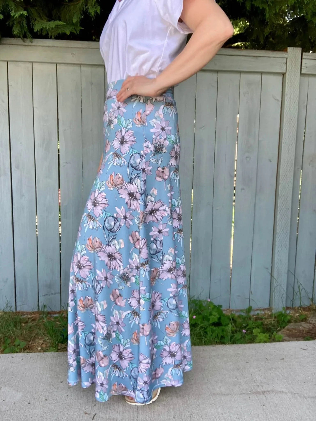 A person models a long, flowing skirt with a blue floral pattern.