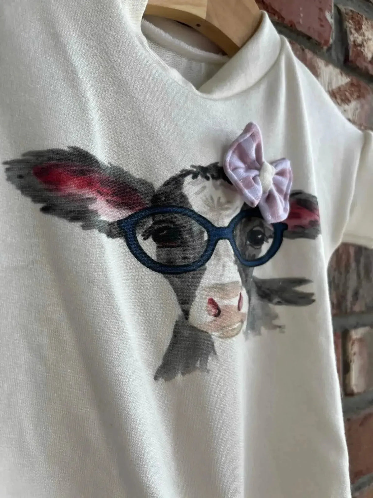 Cute cow print fabric panel with a cartoon calf wearing glasses and a pink bow.