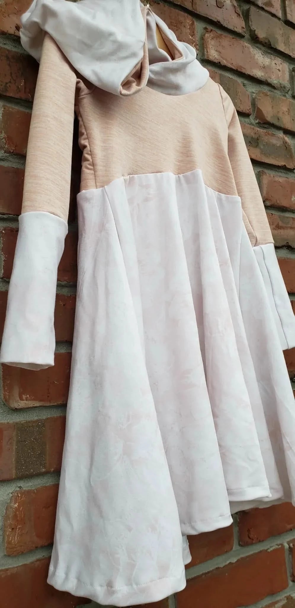 A light pink and white floral dress with a solid pink top and long sleeves.