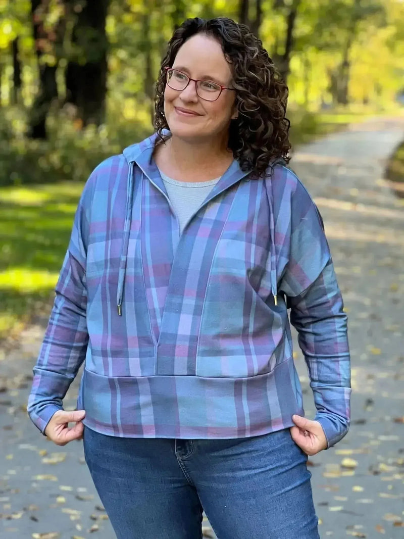 Woman wearing a blue and purple plaid hoodie with jeans.