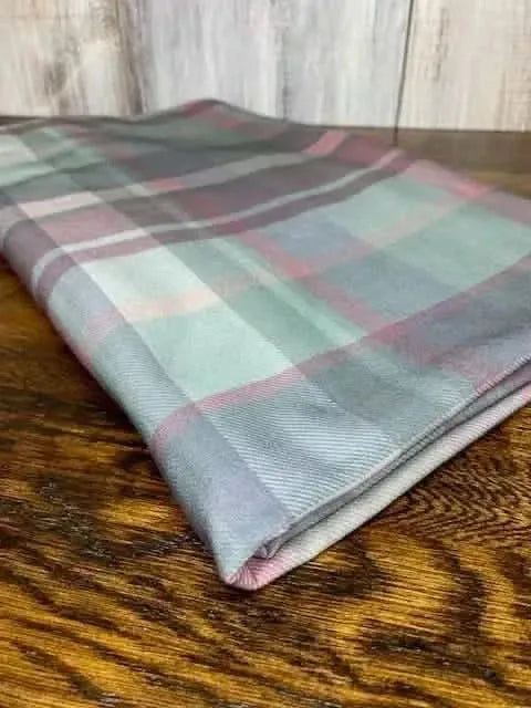 Dark Christmas plaid fabric with festive green, pink, and gray holiday print.