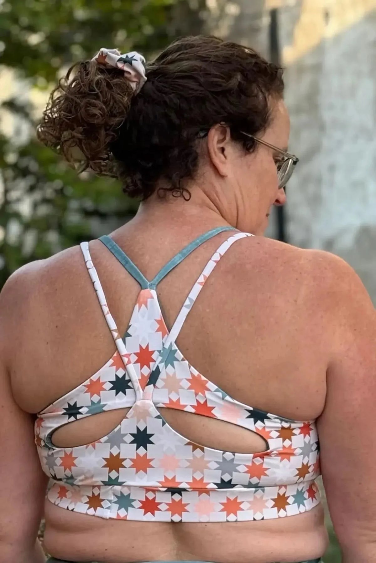 Rear view of a woman wearing a white sports bra in Dawn Horizon geometric print fabric.